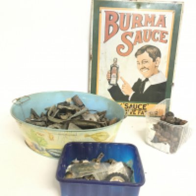 A collection of metal detector finds, a vintage enamel Burma Sauce advertisement, leather buttons and military cap badges