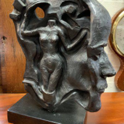 A carved terracotta sculpture mounted on a wooden plinth of Freudian design signed Mary Quinn 1988. 43cm x 32cm x 14.5cm