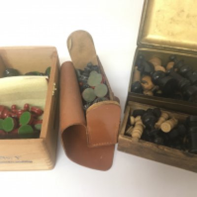 A collection of turned wood chess pieces and painted metal chess pieces.