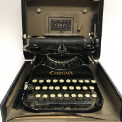 A corona typewriter and a set of gold weighing scaled with weights.