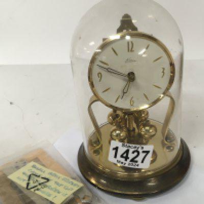 Withdrawn-A German made brass anniversary clock under a glass dome with key. NO RESERVE