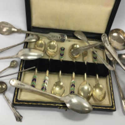 A cased set of enamel spoons together with a silver tea caddy spoon and various other spoons