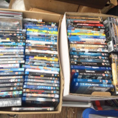 Two boxes of BluRays and DVDs plus a sealed Laurel & Hardy DVD gift tin.