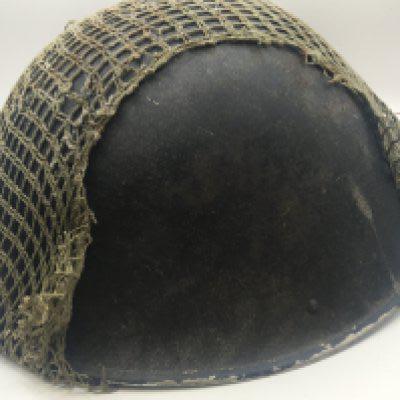 A British Military post Second World War helmet with netting cover and fitted with interior helmet lining