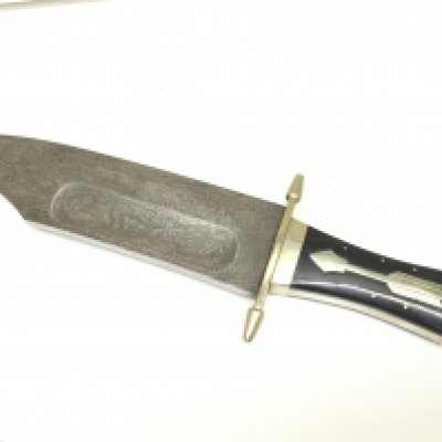 An American vintage Bowie Knife with an inlaid horn grip inlaid with an arrow symbol and Damascus blade.