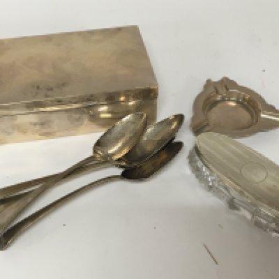 A table top silver cigarette box Birmingham hallmarks and no personal inscriptions 16cm x 9.5cm and in good condition Four George III silver table spoons a silver topped cut glass box and a silver ashtray.