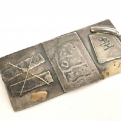 A silver and gold abstract brooch with chinese symbols. Postage category a