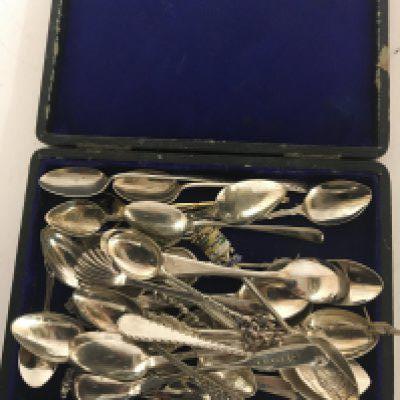 A case containing silver and white metal tea and desert spoons.