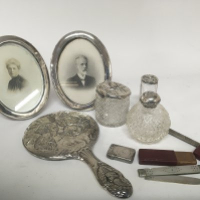 A pair of silver oval shaped picture frames a silver backed hand mirror a mother of pearl and silver fruit knife Vesta case and pencil holder etc.