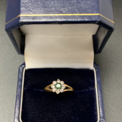An 18ct gold emerald and diamond cluster ring, Size H. (A)