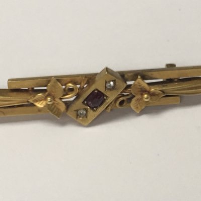A Edwardian 15 ct gold brooch inset with small central ruby flanked by diamond chips total weight 4 grams.