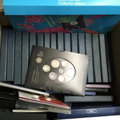 A box containing British proof annual coin sets and a full London 2012 sports collection collectors album. Postage category C