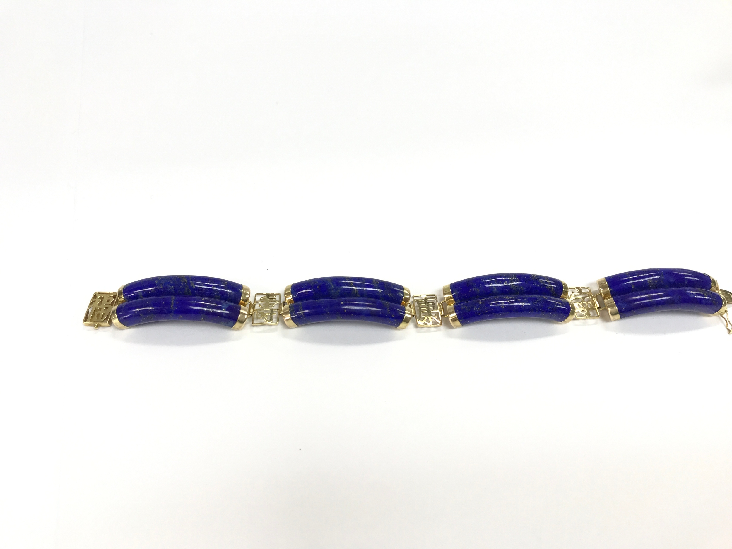 A 14k Chinese style link bracelet made with curved lapis lazuli gemstones and yellow gold calligraphic. 19cm length.