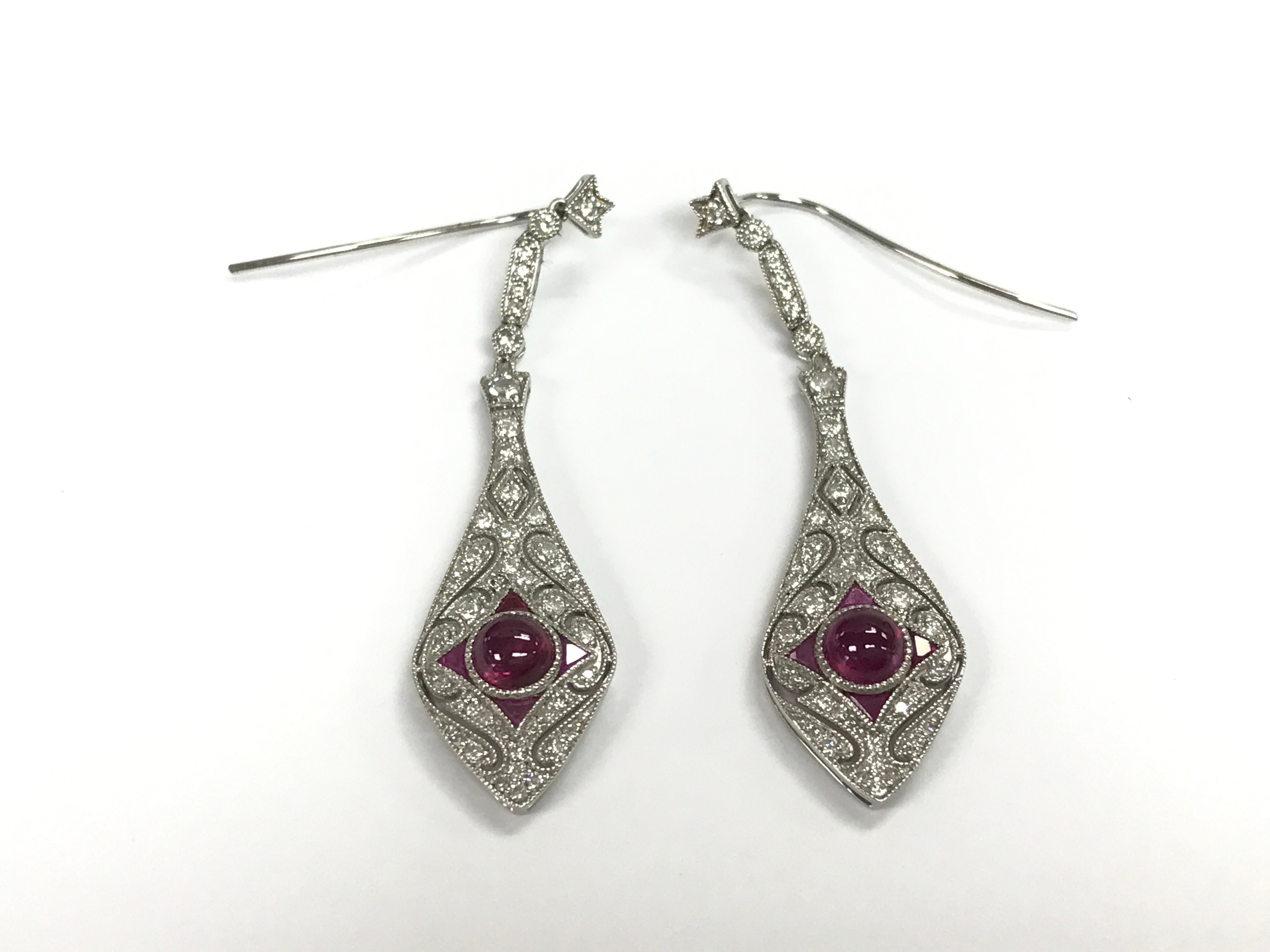 Pair of platinum art deco style drop earrings set with a central cabochon Ruby and diamonds set filigree patterned surround with fishhook backs. Rubies 0.80ct and 0.30ct diamonds 