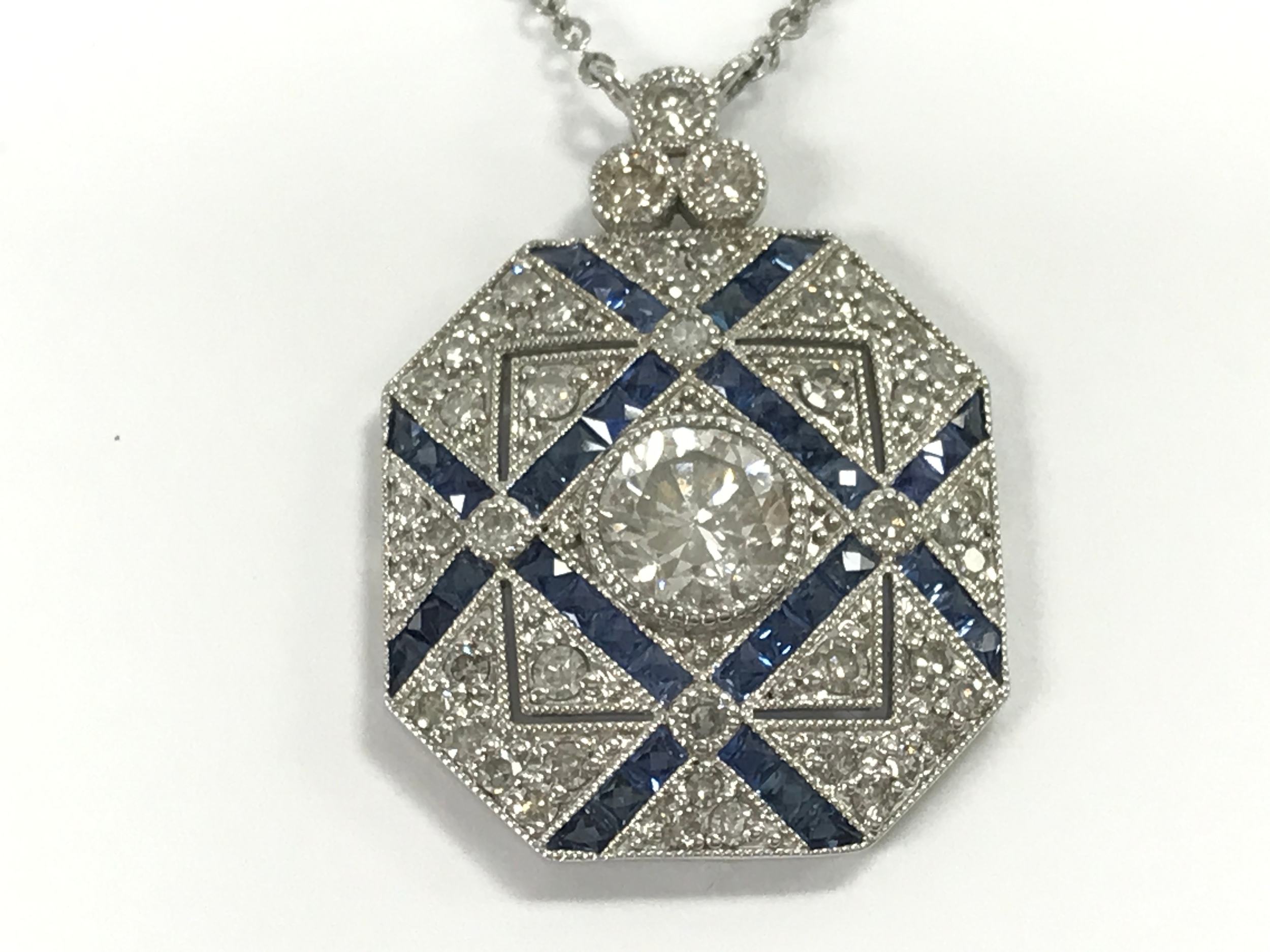 Platinum panel style pendant set with diamonds and sapphires on a platinum chain. Central diamond 1.01ct surrounding diamonds 0.58ct sapphires 0.58ct approximately.