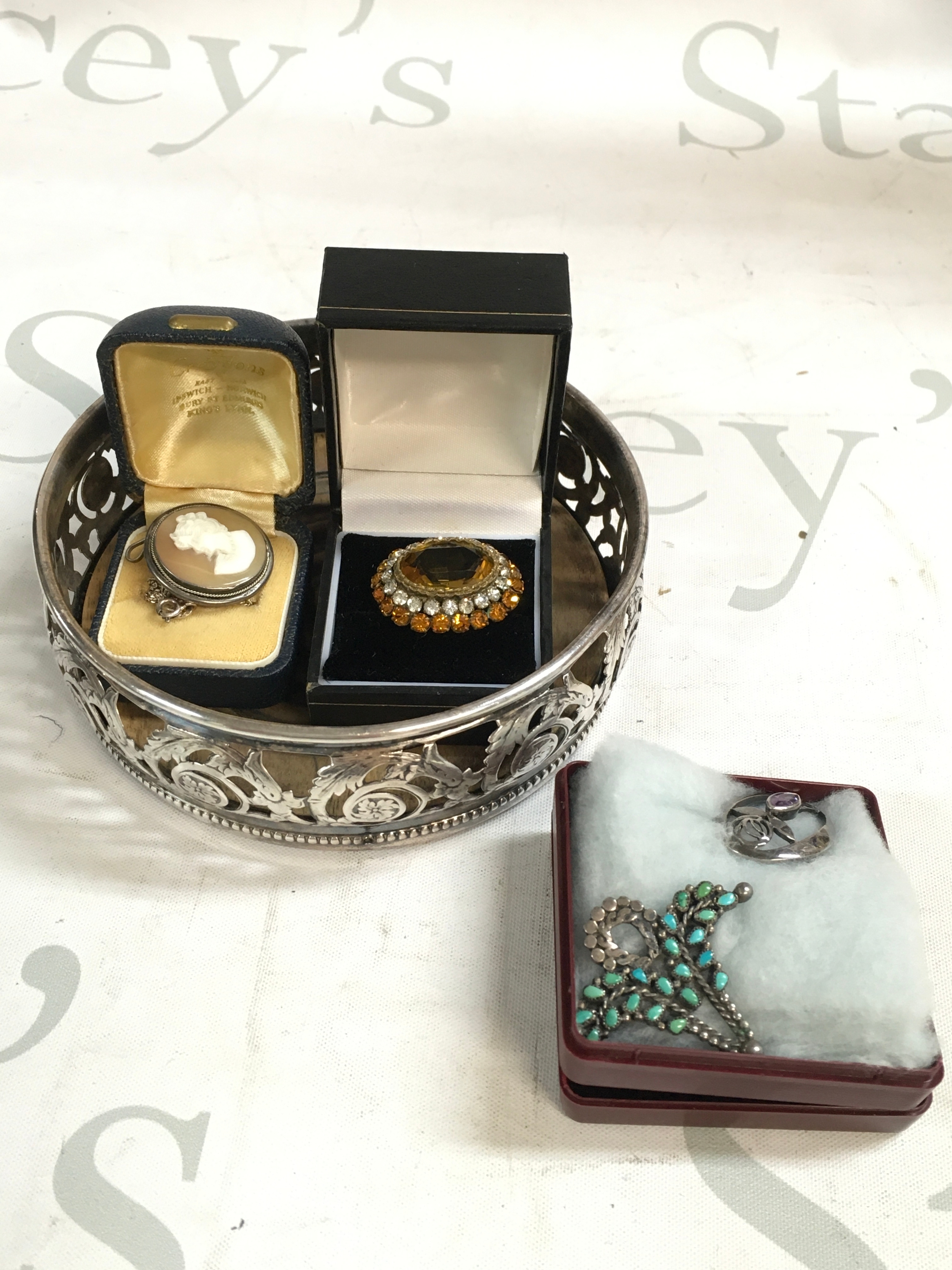 A collection of three broaches and a white metal coaster 