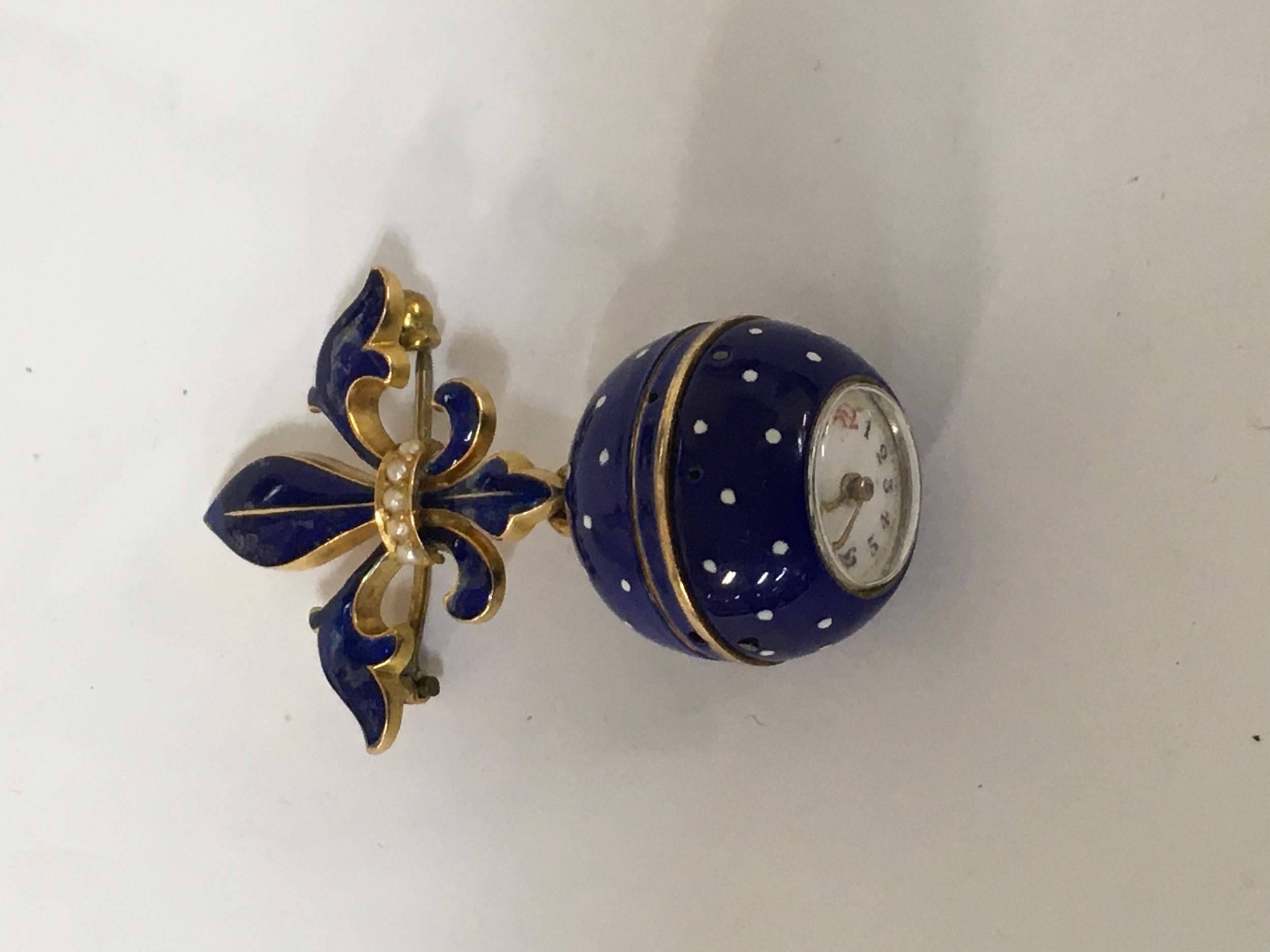 A lady's yellow metal and blue enamel ball fob watch, having Fleur De Lis pin.Approx: L4cm