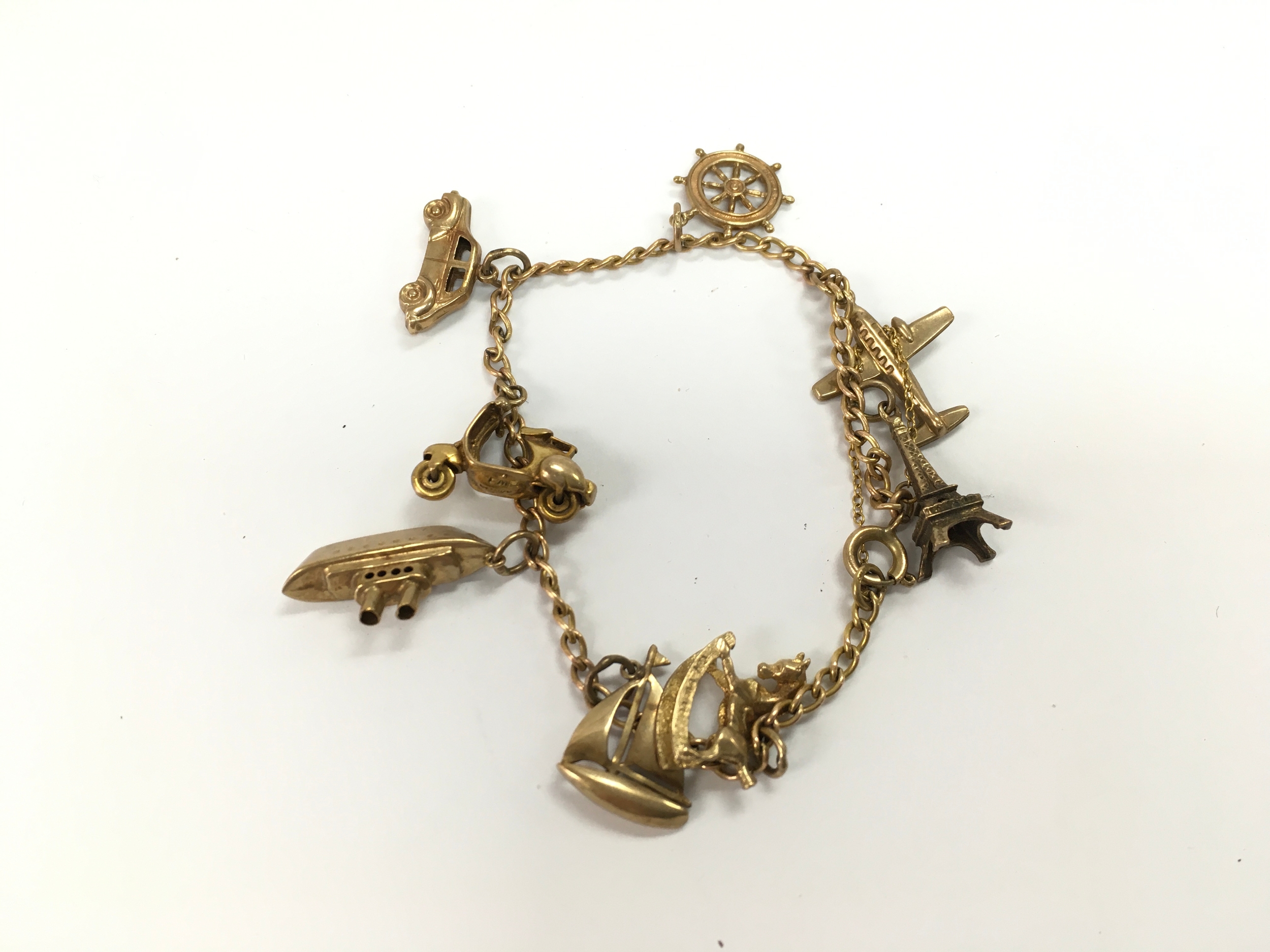 A 9ct gold charm bracelet with assorted charms. 12.90g