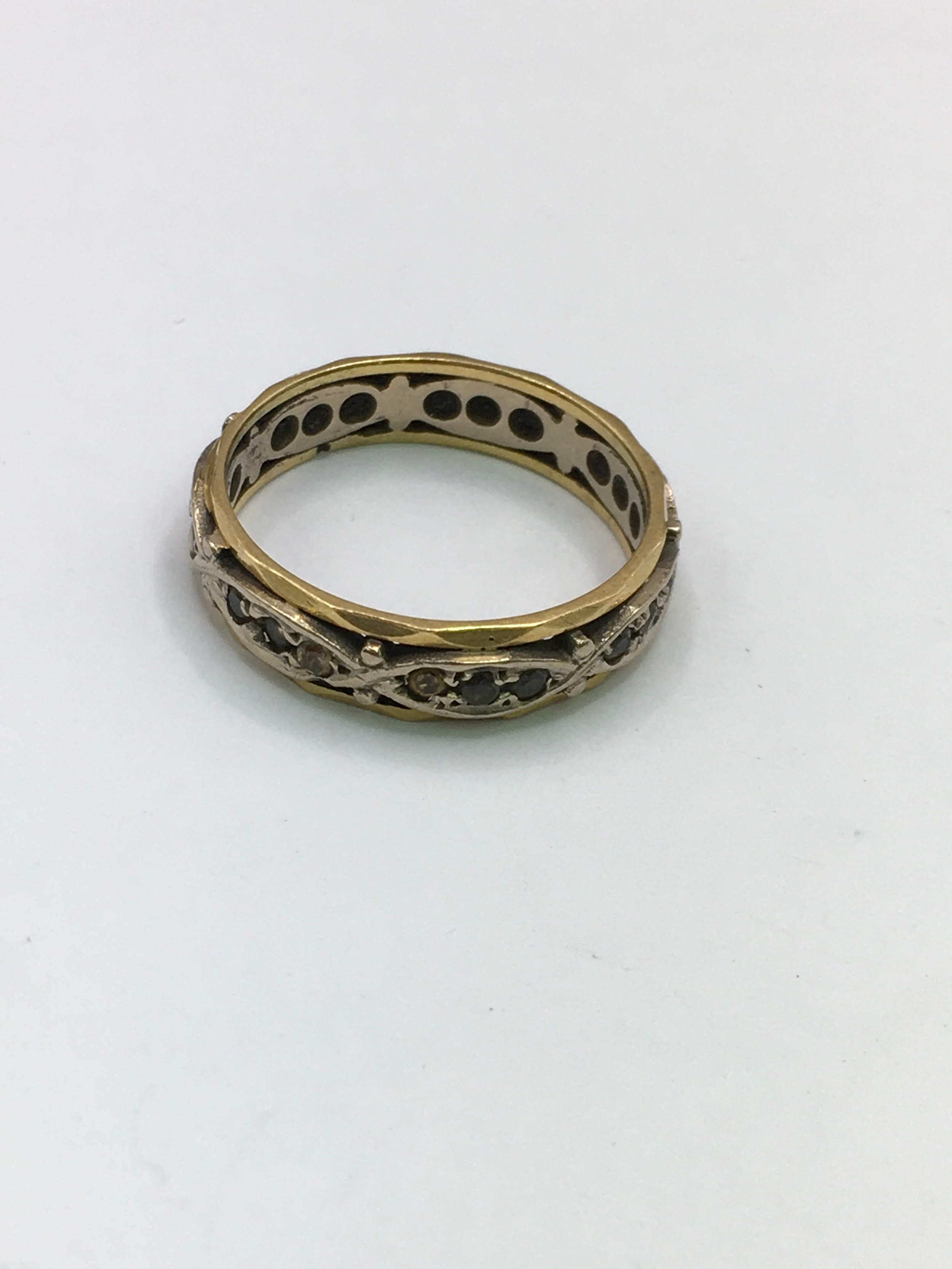 An unmarked yellow and white gold band ring set with small brown sapphires. Approx size M/N
