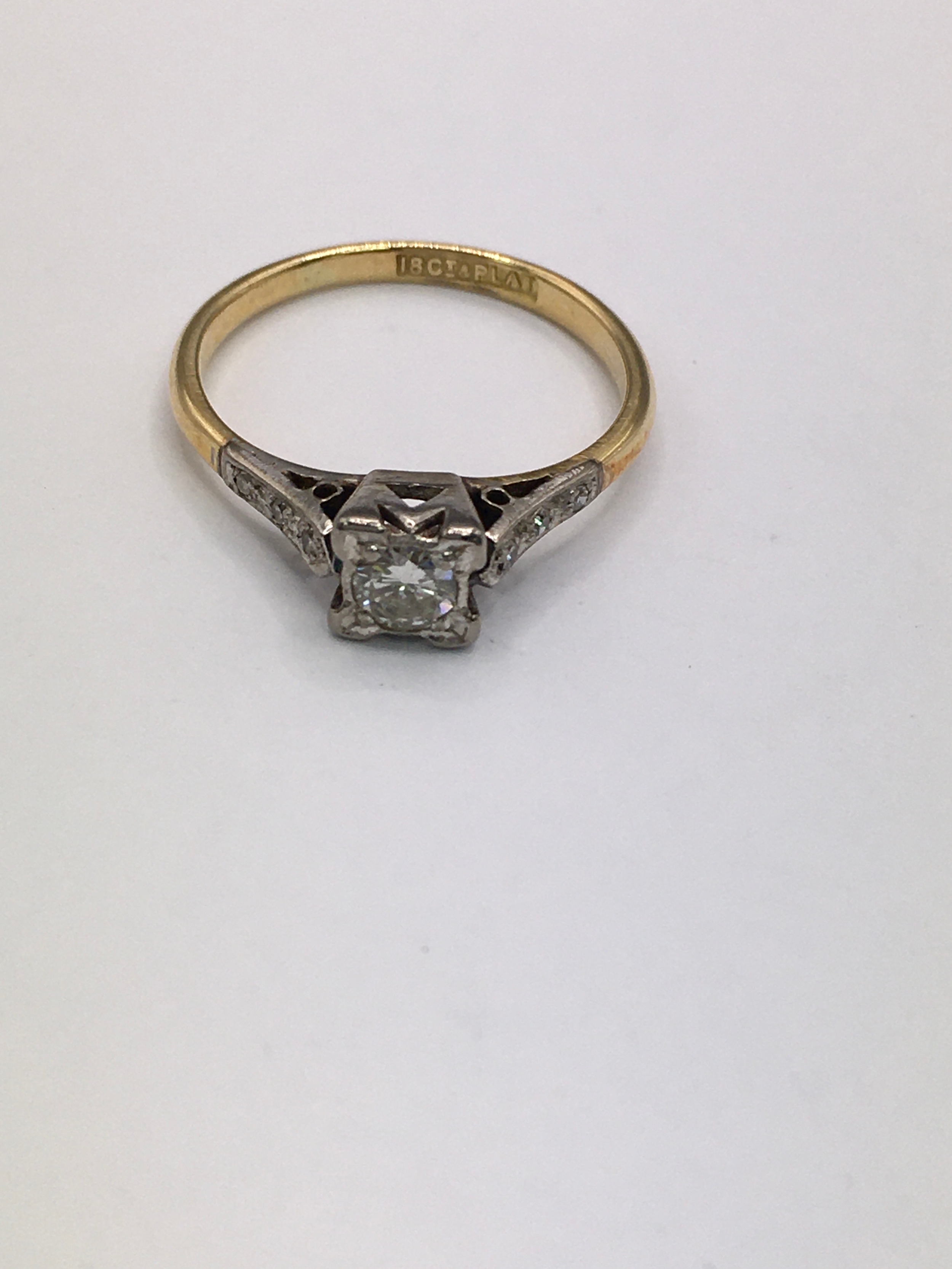An 18ct gold ring having square cut mount set with diamond, flanked by smaller chip stones. Approx size M.