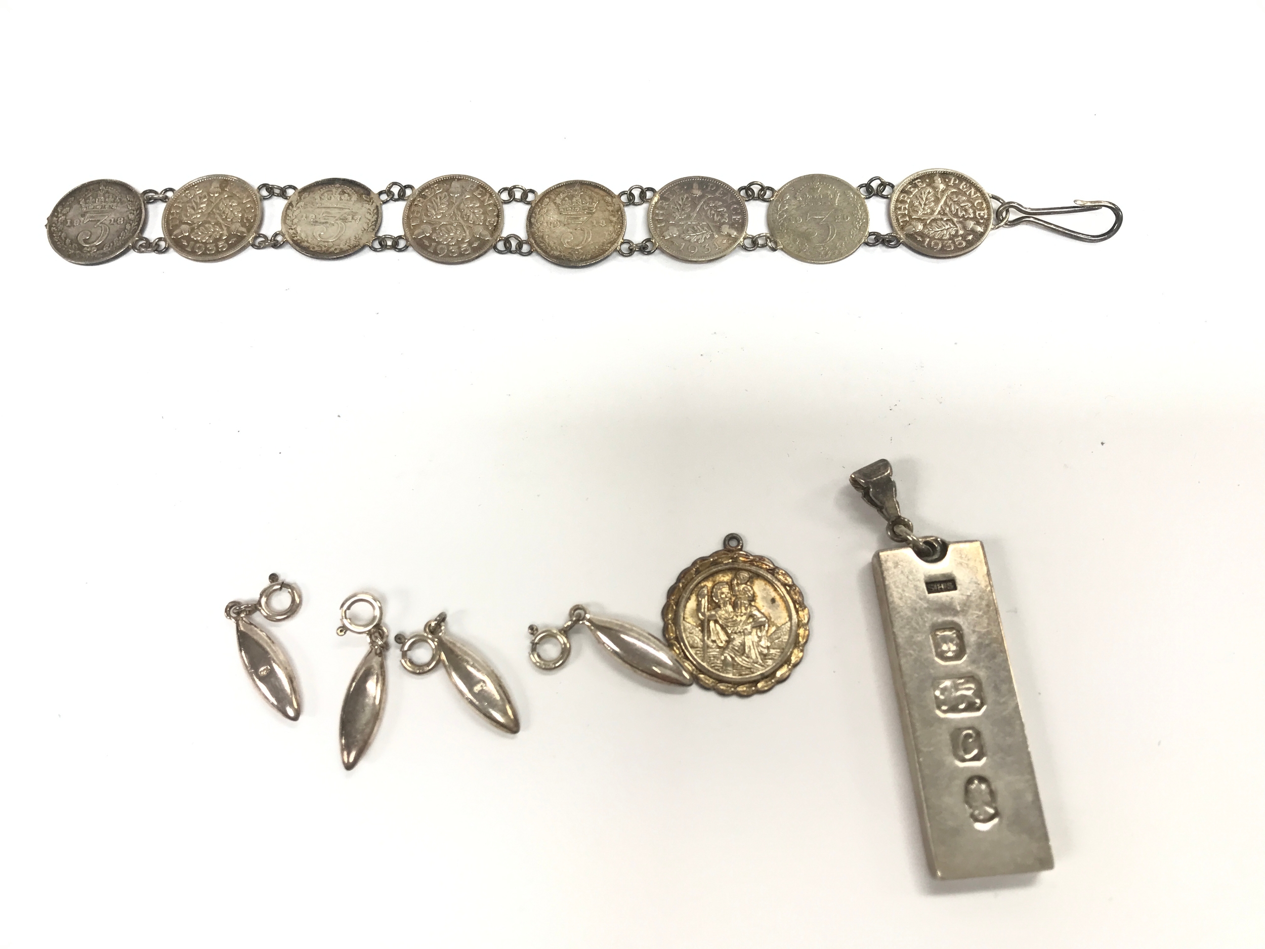 A silver ingot pendant, silver pendants and a silver coin bracelet. 55g
