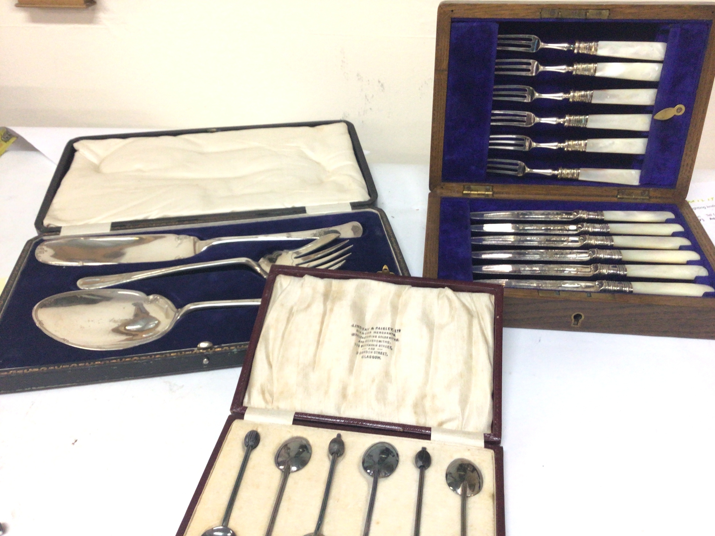  An oak case containing silver plate and mother of pearl fruit knifes and folks a cased set of silver plated serving spoons and coffee spoons. (3) 
