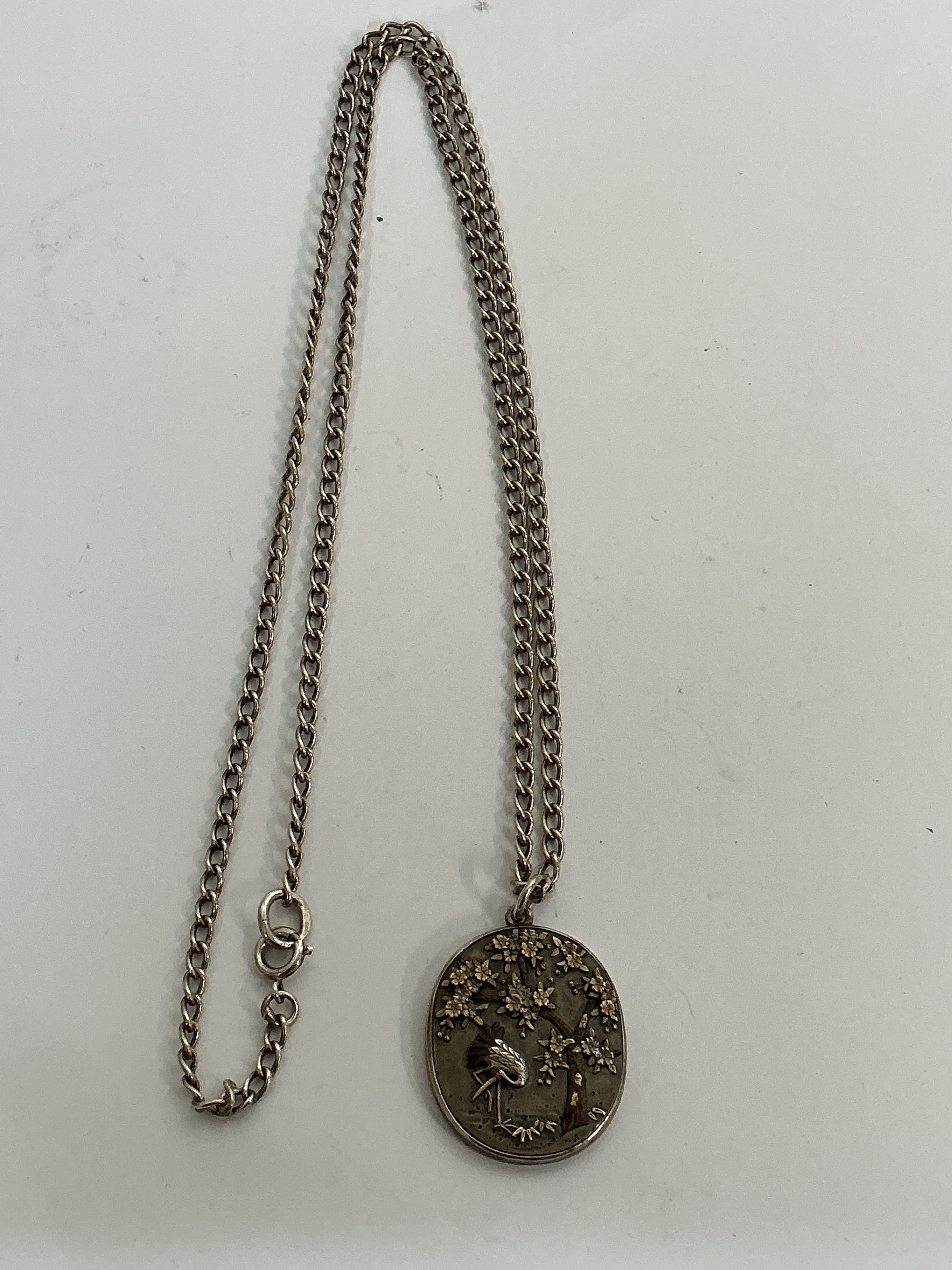 A Japanese style pendant necklace decorated in relief with a stork, on sterling silver chain.Approx 35cm x 2cm wide 24.14g