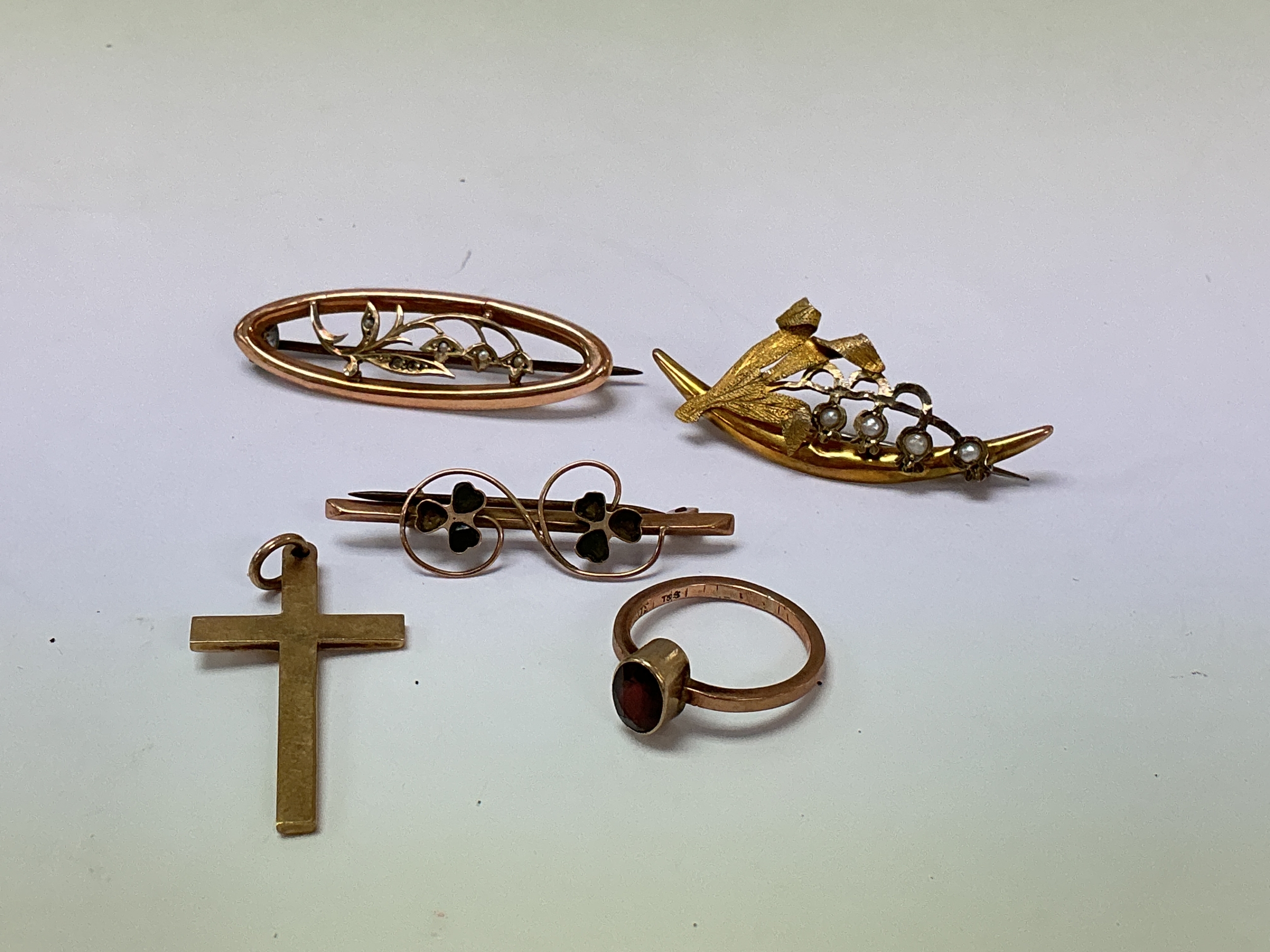 A small group of 9ct gold jewellery comprising three bar brooches, a cross and ring set with a red stone. 