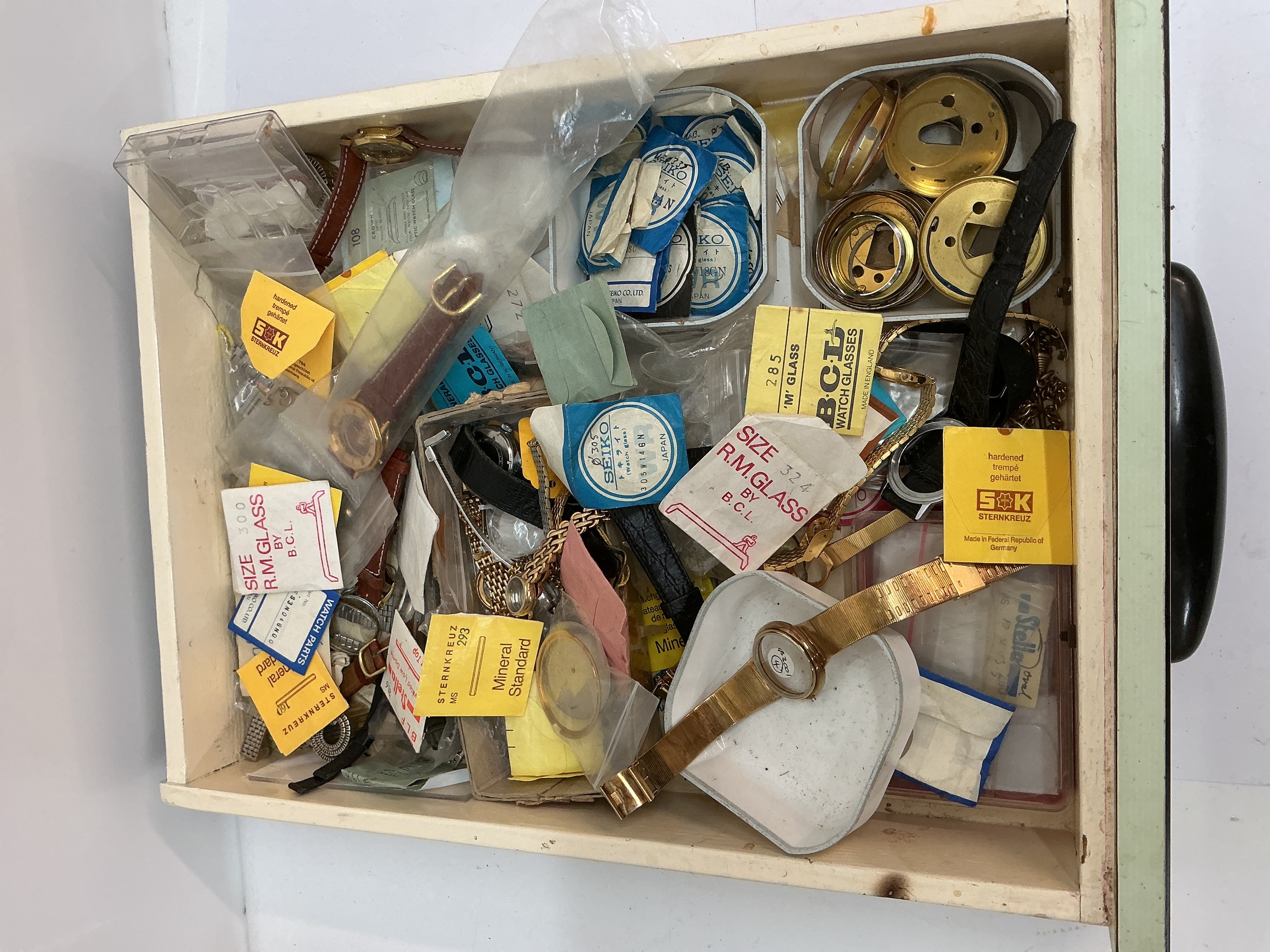 A tray containing assorted watch parts and fittings
