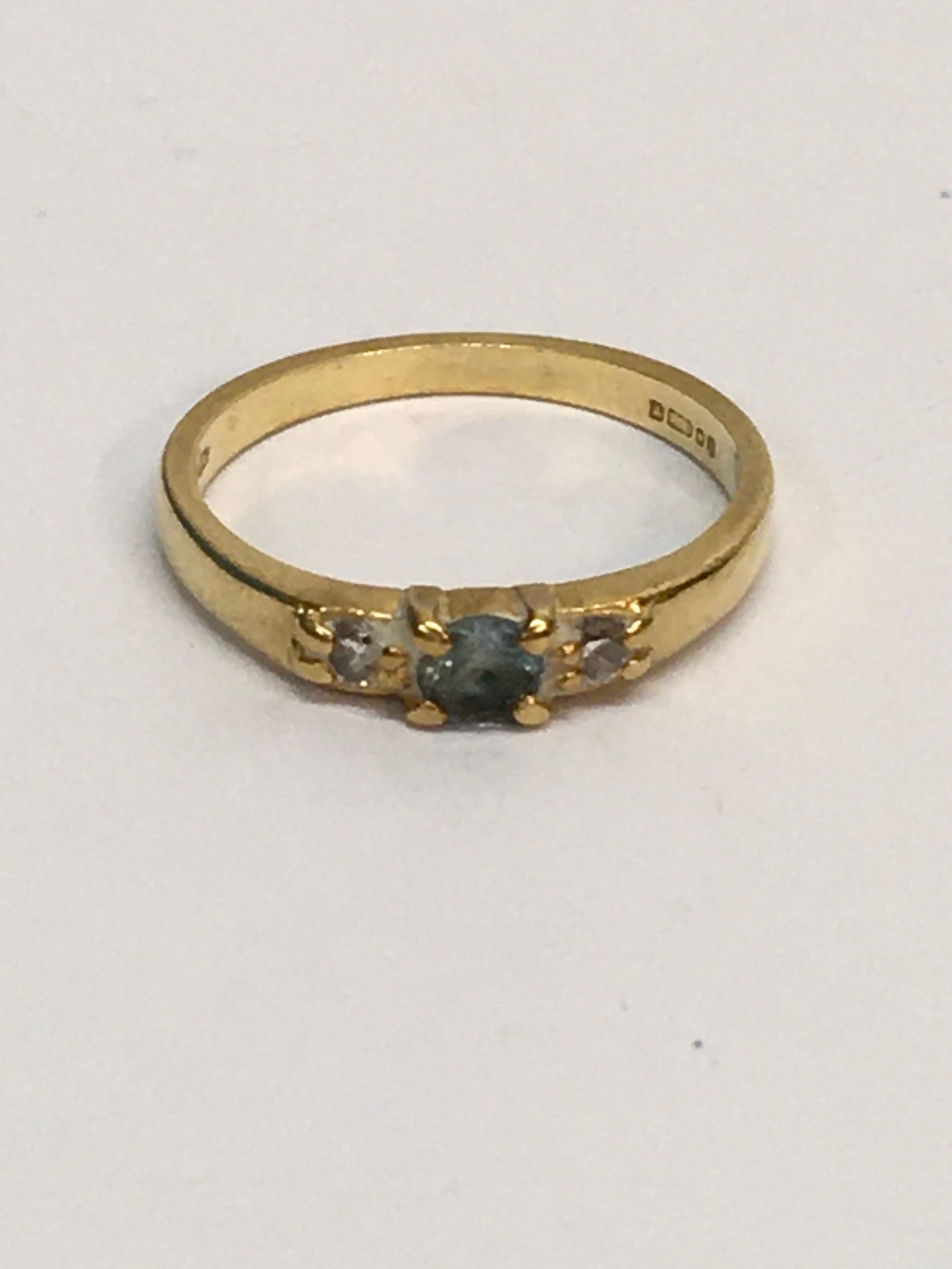 An 18ct 750 gold ring set with a blue stone flanked by white chips.  Approx size O, 3.30g
