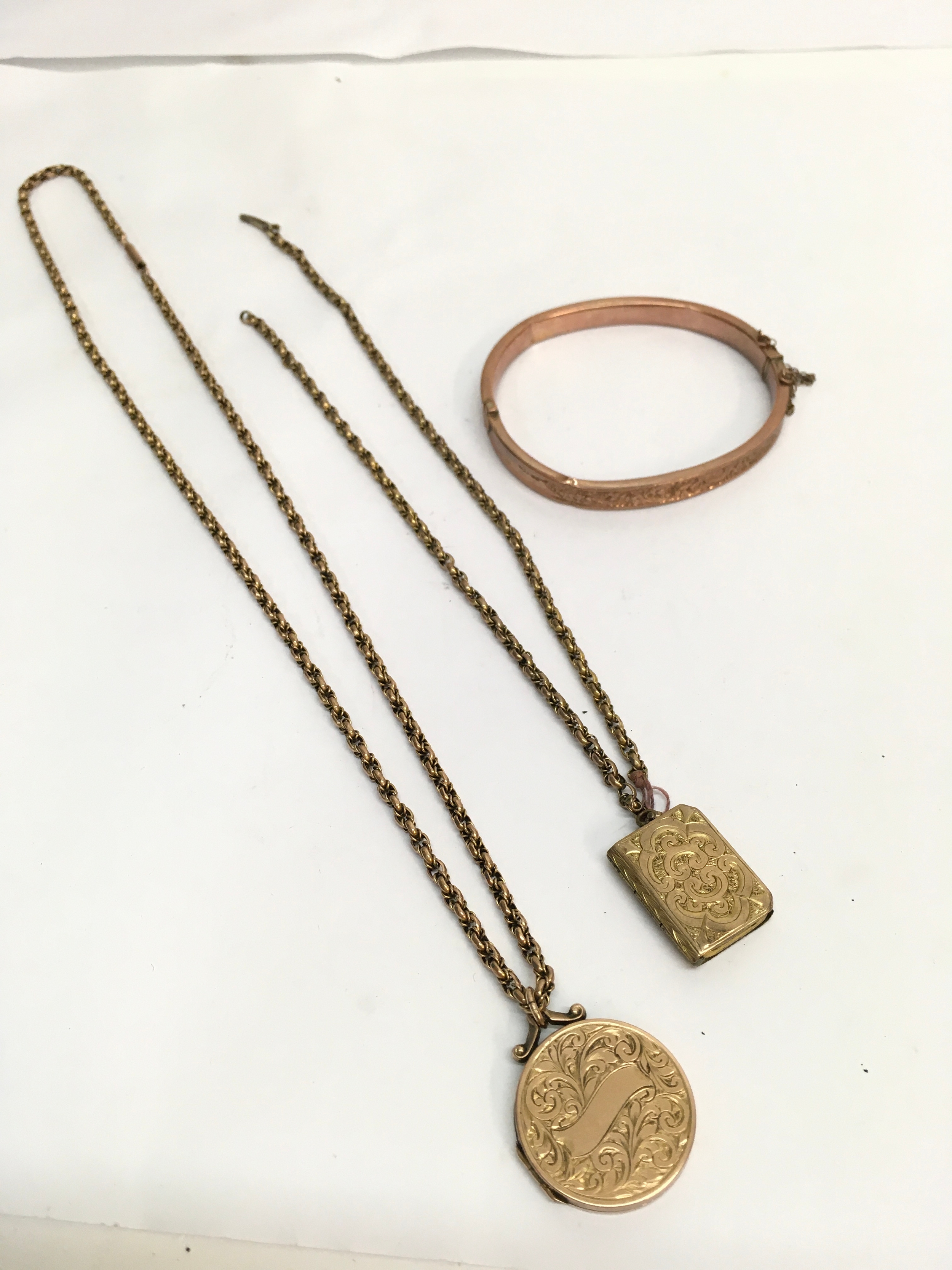 A 9ct gold Victorian locket plus another yellow metal example, both on 9ct gold chains, and 9ct rose gold hollow bangle.A/F. Approx: 30g