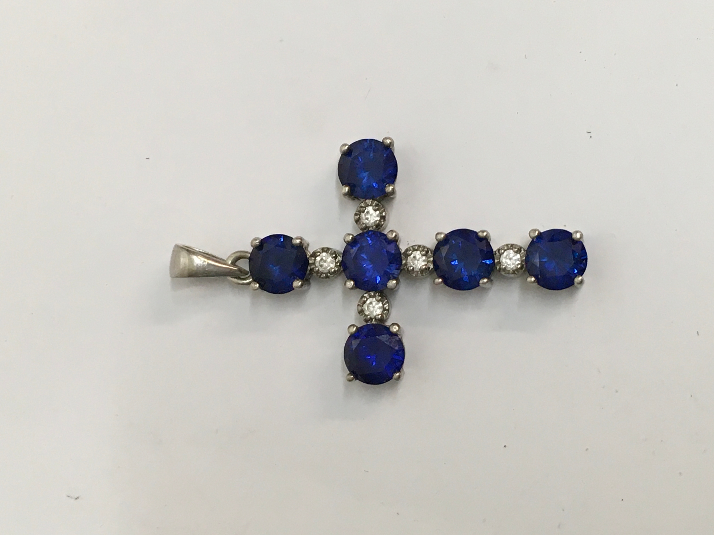A possible 9ct white gold cross set with blue stones. Approx: L4.5cm, 4.90g. Indistinct mark, untested.