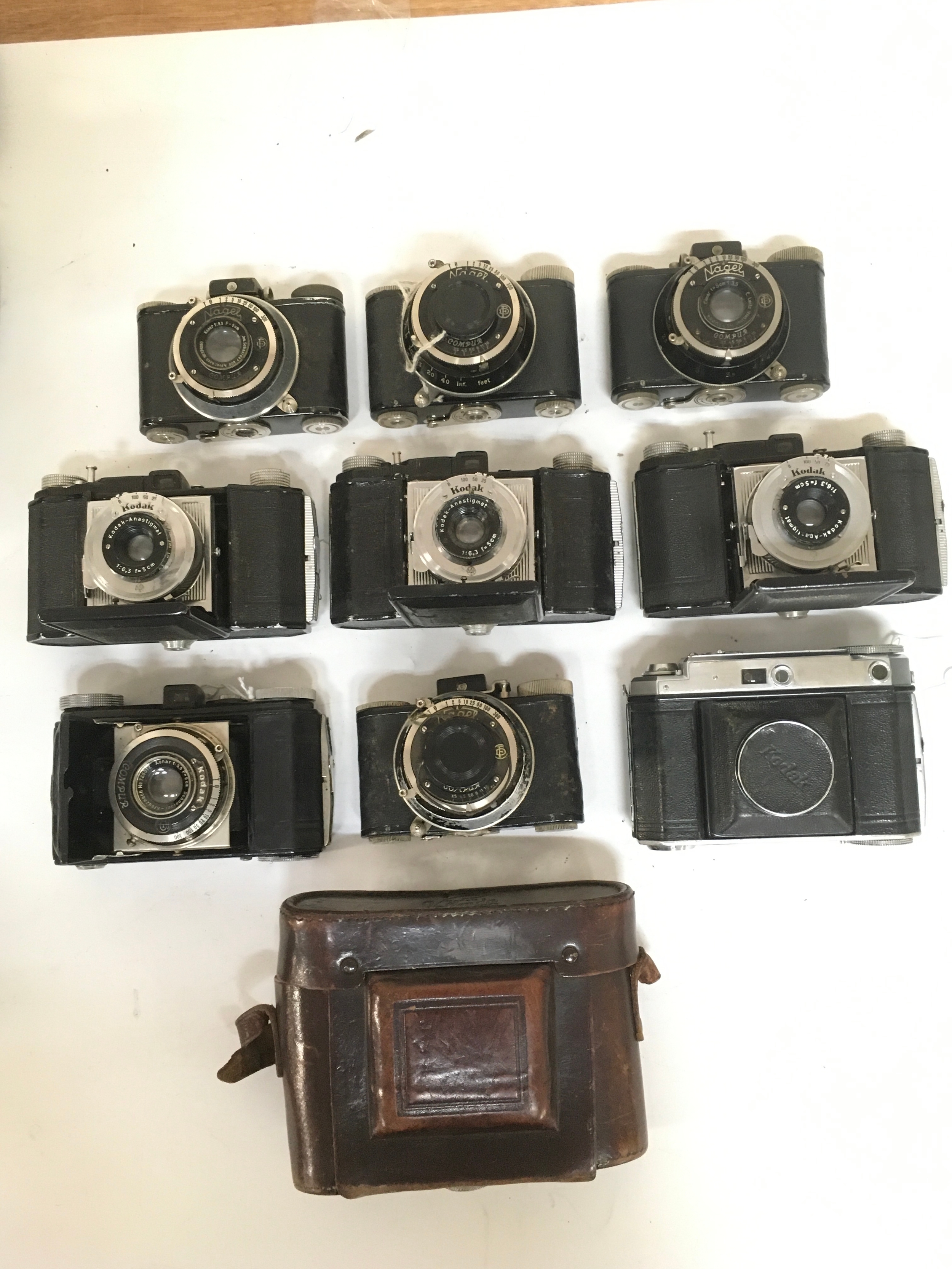 10 items; x9 Cameras. 4 Nagel Compur Cameras with 2 varying designs. 3 Kodak - Anastigmat. 2 Kodak Compur. 1 Kodak Vollenda 620 camera holster carrier.