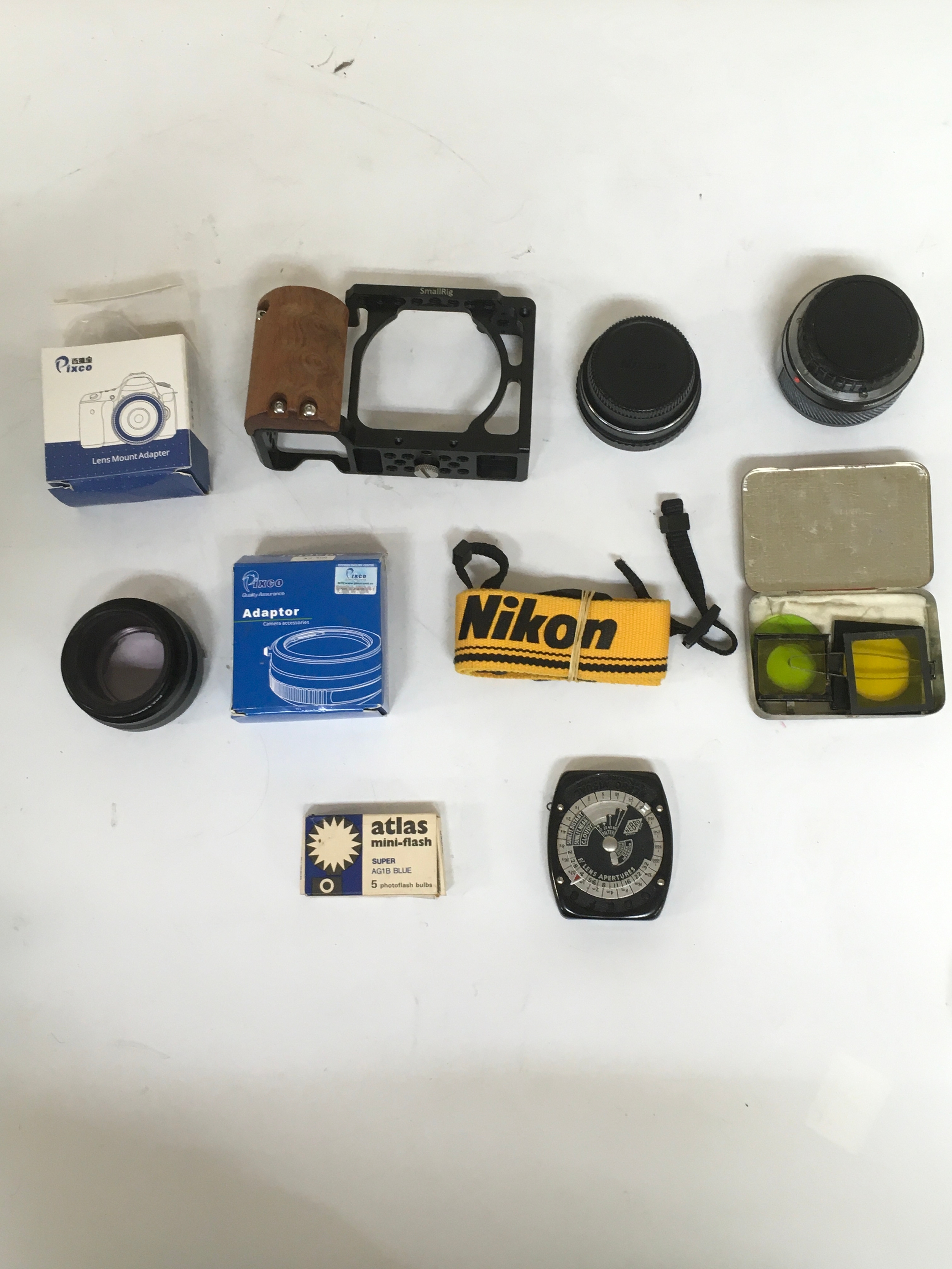Assortment of 10 items. Camera parts and lens aperture lens filters. Adapters, camera rig and miscellaneous camera lenses. Additional Nikon camera strap.