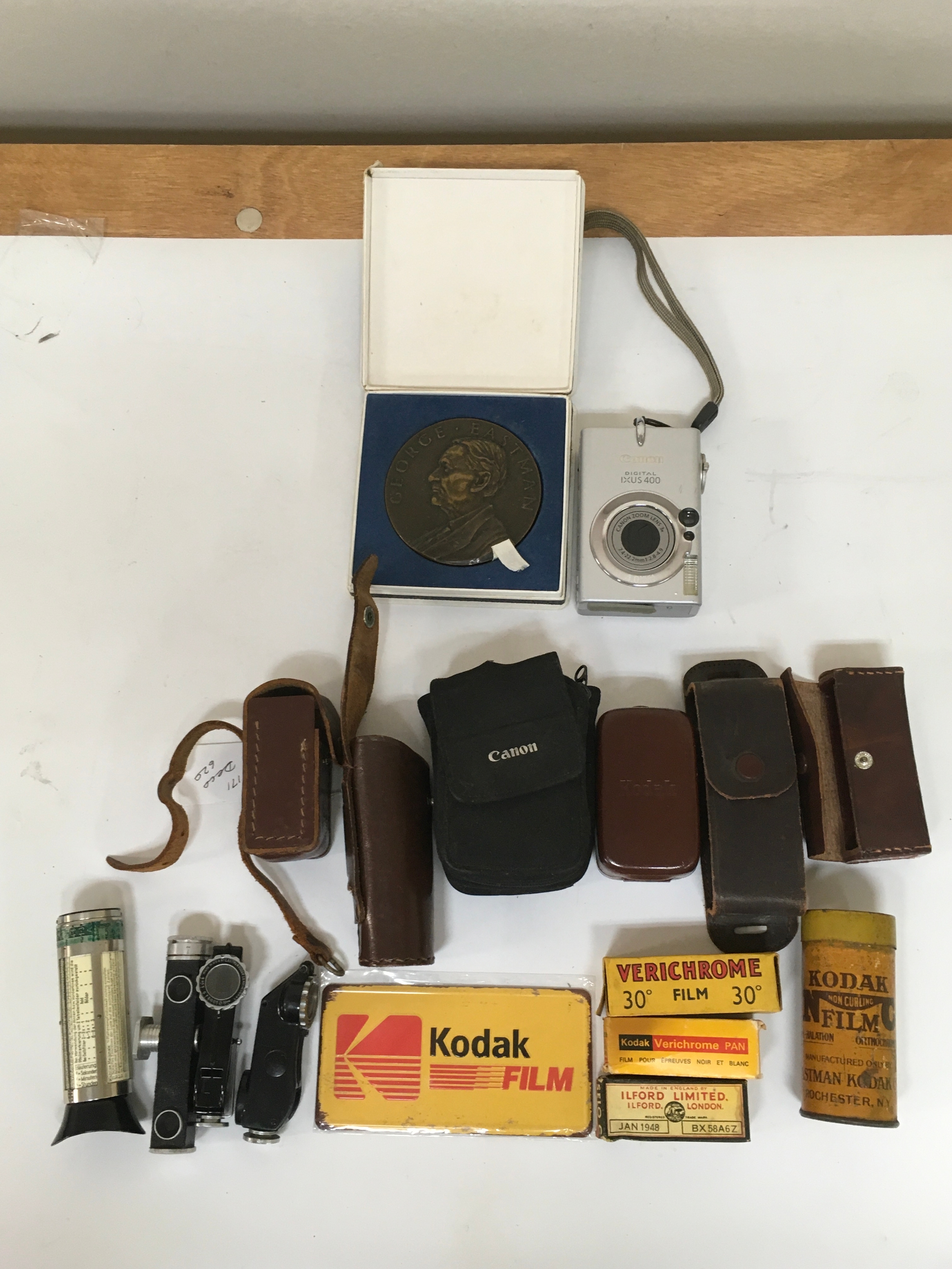 Miscellaneous lot . A Canon digital IXUS 400. A Kodak 25 years service medal  assortment of camera accessories including; film ,range finders, pouches and a Kodak film magnet.