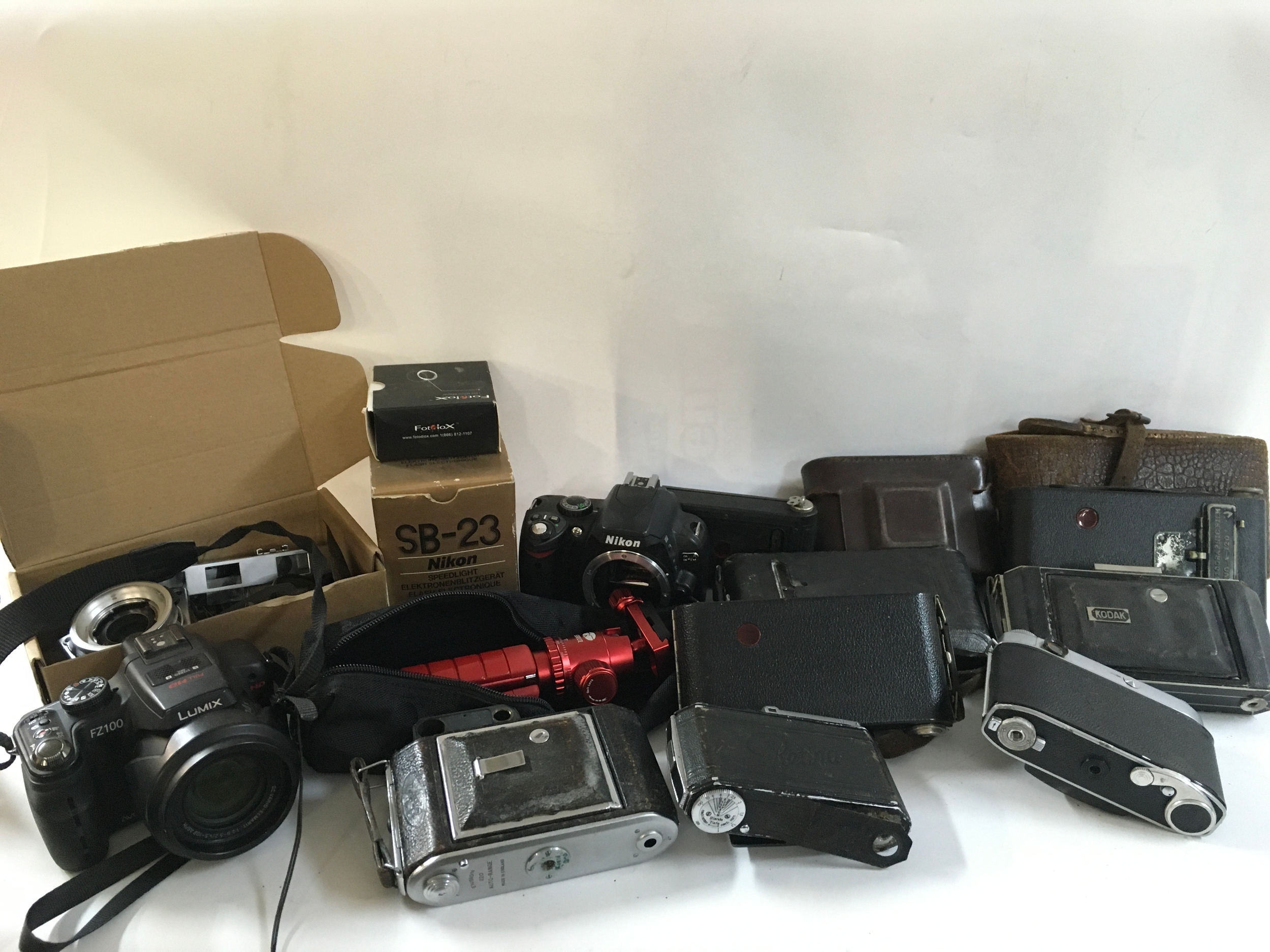 A collection of various vintage cameras including Kodak and Retina cameras and equipment like a speedlight, a mini tripod and others. 