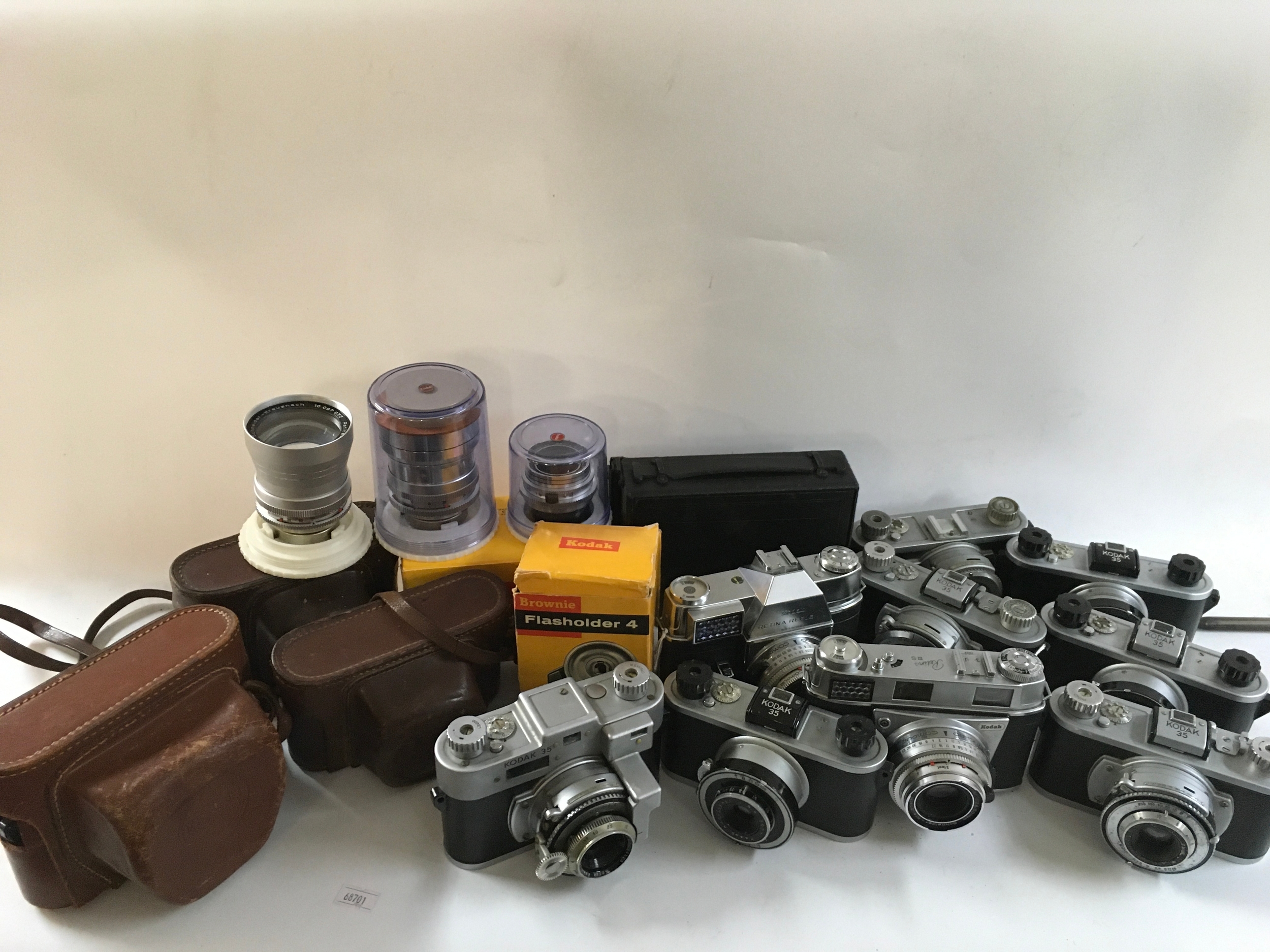 A collection of 13 Kodak cameras, a flashholder, an instamatic field case and three different lenses. 