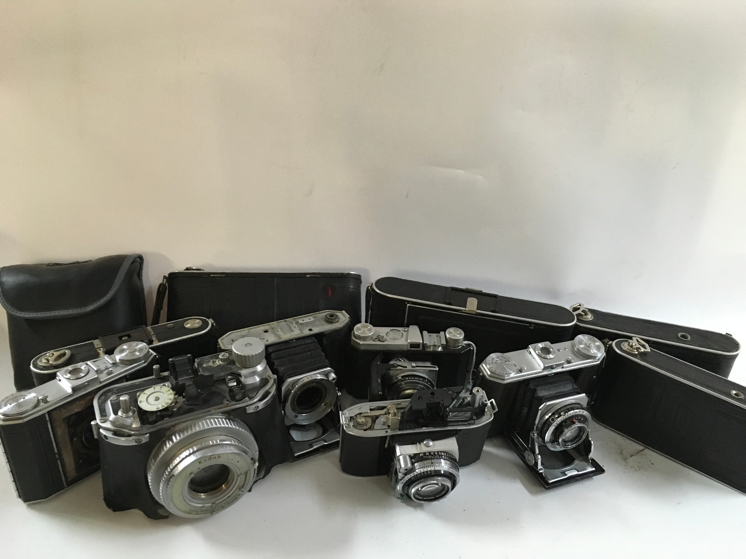 A collection of 11 different cameras featuring Kodak and Nagel cameras and a some binoculars. 