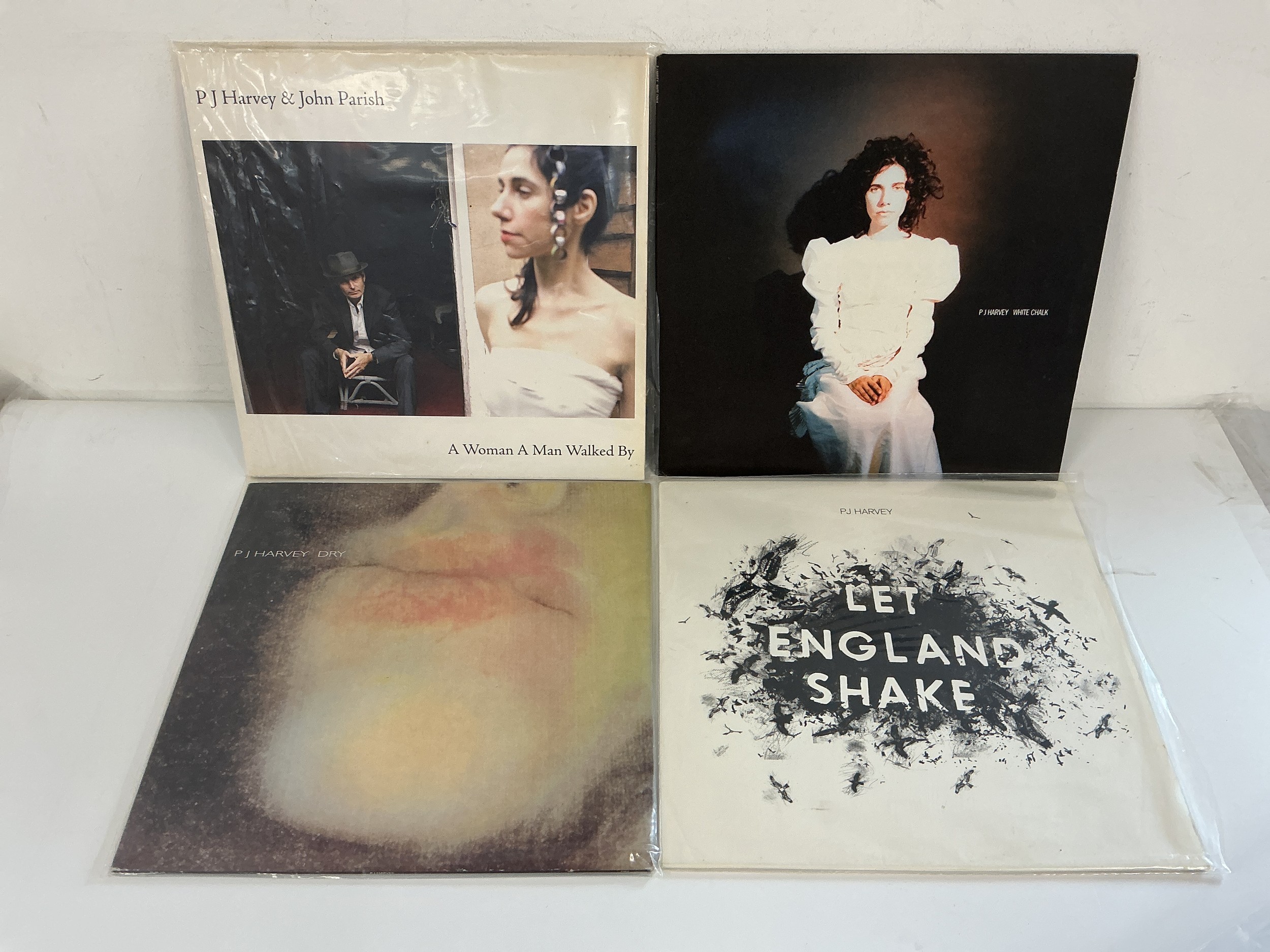 Four PJ Harvey LPs comprising Let England Shake, Dry, A Woman A Man Walked By and White Chalk.