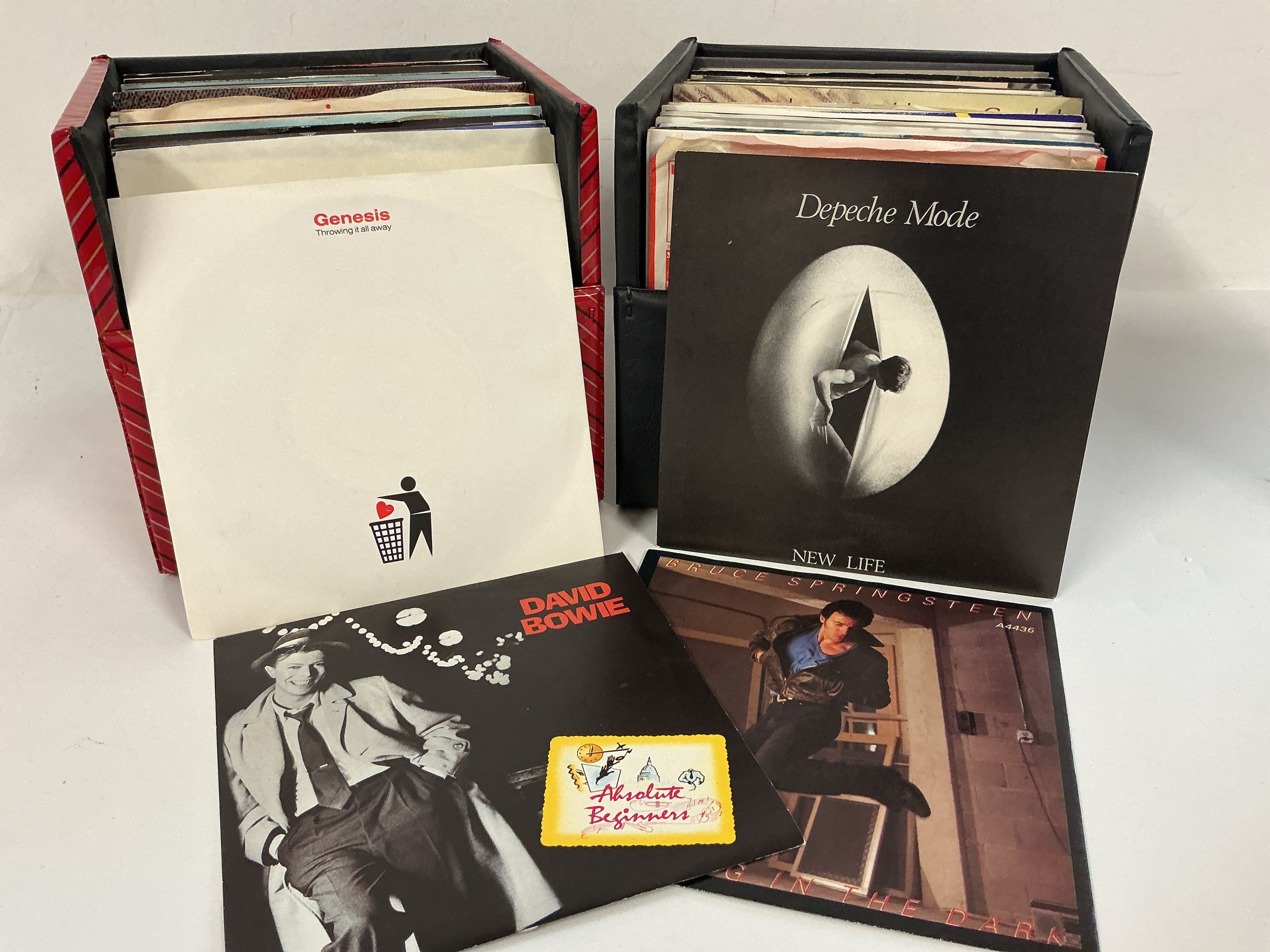 Four record cases of 7" singles and EPS by various artists including David Bowie, Depeche Mode, John Lennon and many more.