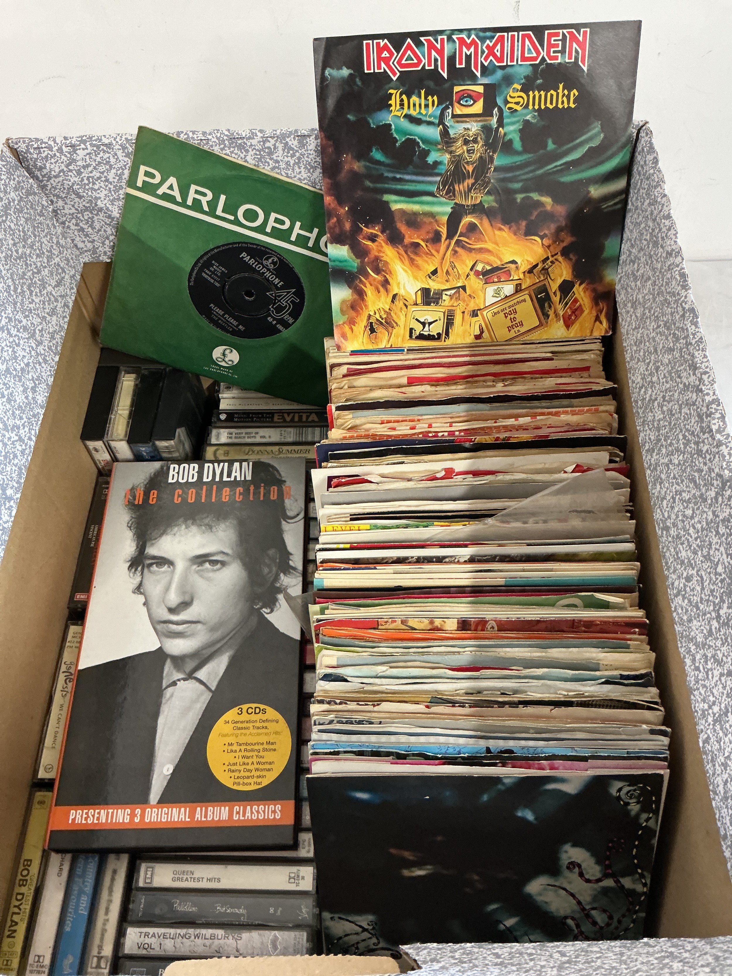 A collection of 7" singles, EPs and cassettes by various artists including The Beatles, Iron Maiden, The Cure and others plus a Bob Dylan CD long box set.