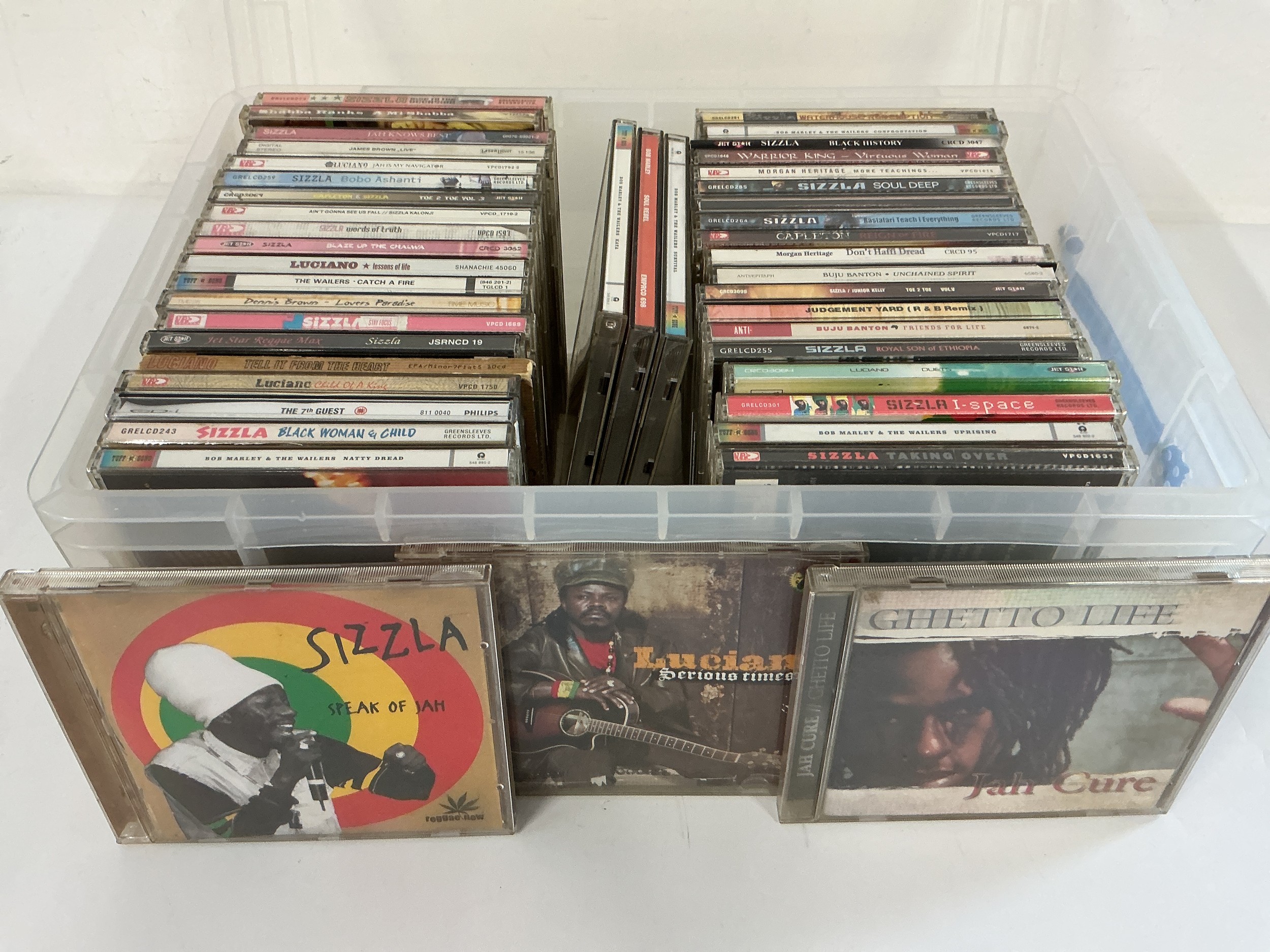 A box of reggae CDs by various artists including Sizzla, Bob Marley, Jah Cure and others.