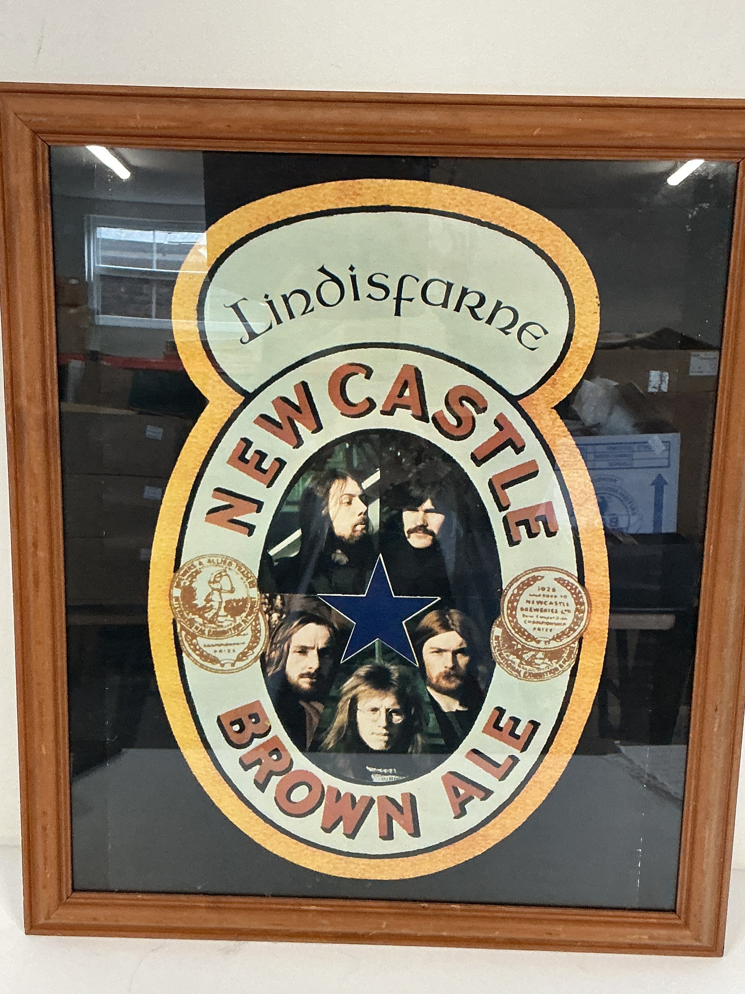 A framed and glazed early 1970s Lindisfarne Newcastle Brown Ale advertising poster, approx 57cm x 67cm including frame.