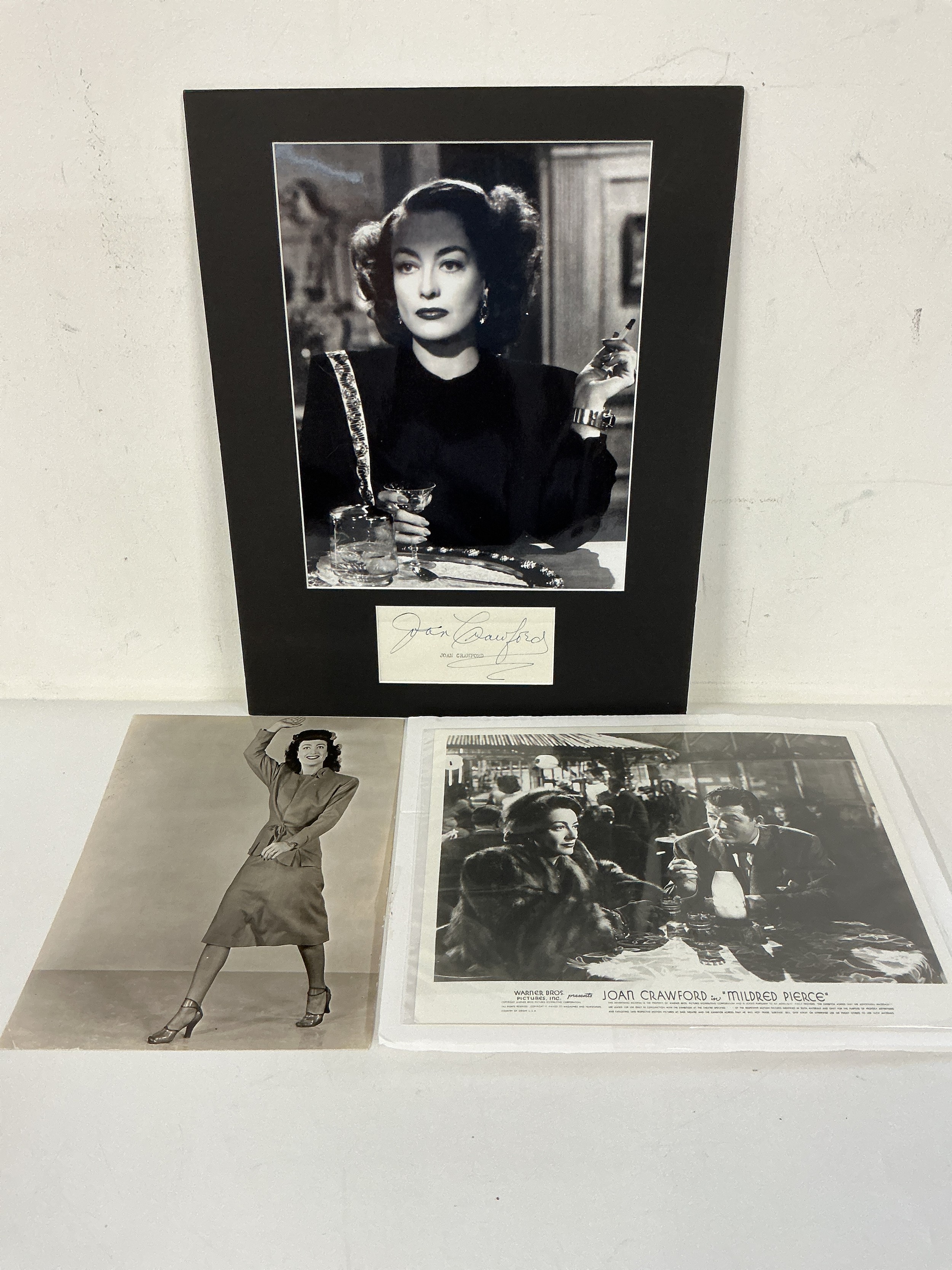 A Joan Crawford autograph and photo mounted on card with a further publicity photograph and a lobby card for the movie Mildred Pierce. Comes with COA.