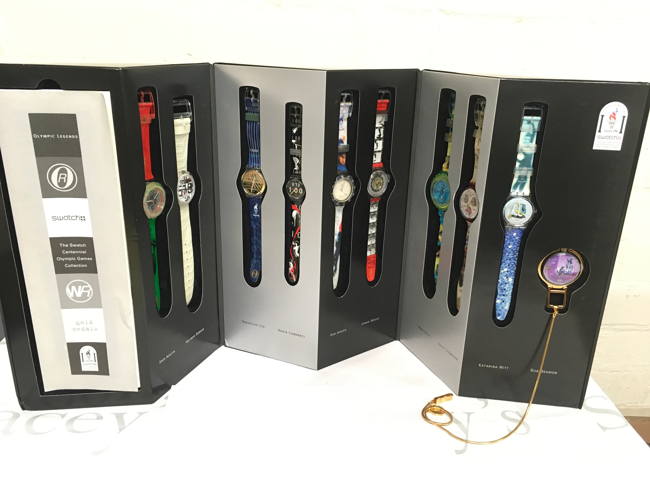 1996 Swatch "Olympic Legends" Centennial Collection watch set featuring ten timepieces honoring famous athletes. The collection includes nine wristwatches and one pocket watch packaged in original black and silver boxes. Featured athletes include Katarina Witt, Mark Spitz, and Edwin Moses, among others.