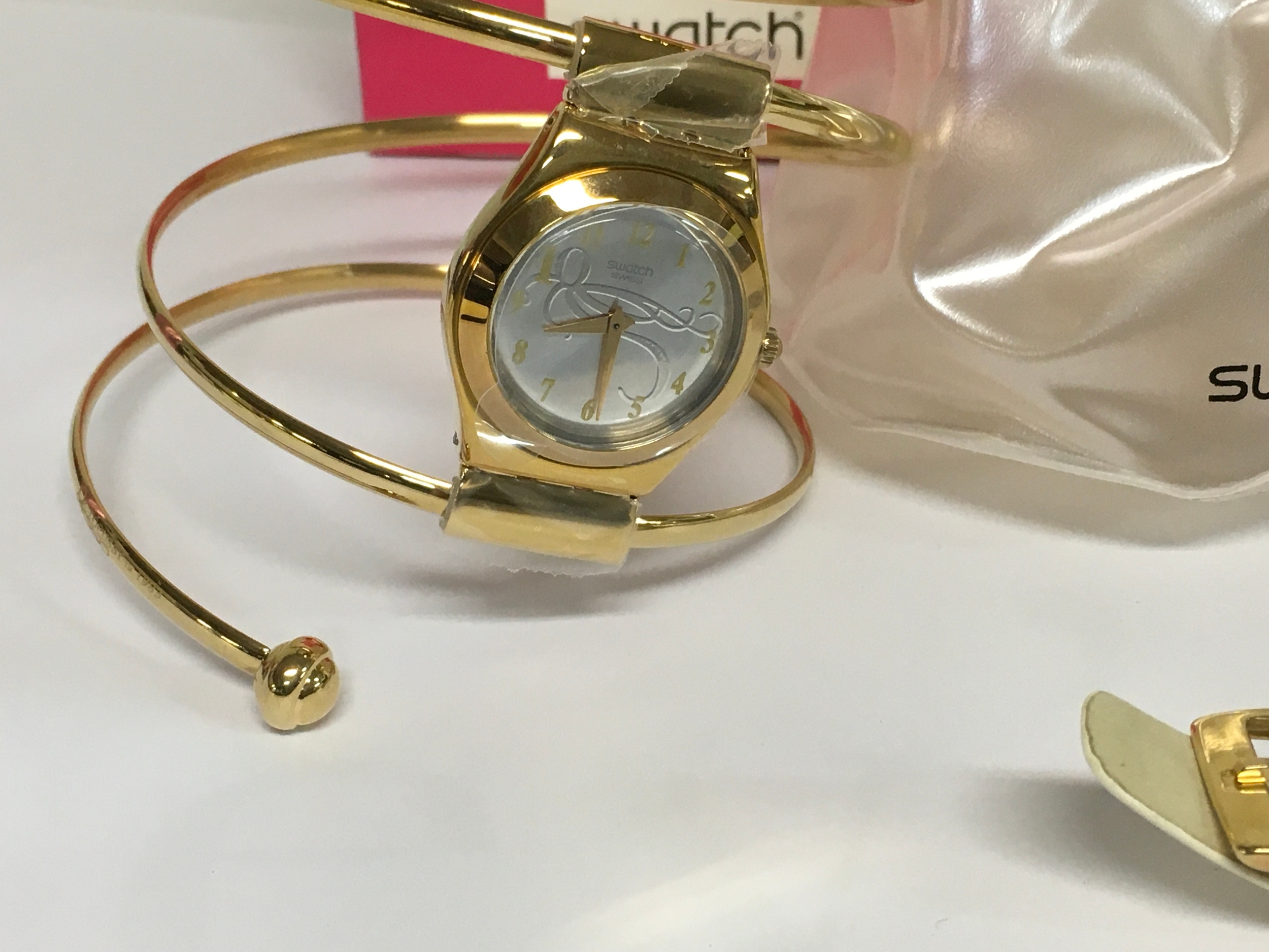 limited edition Swatch Irony Lady "Octopussy" watch, released in 2002 as part of a James Bond collection. The watch features a unique gold-plated coiled snake bracelet designed to wrap around the wrist. It comes with a special gold tin packaging, a white leather replacement strap, and documentation.