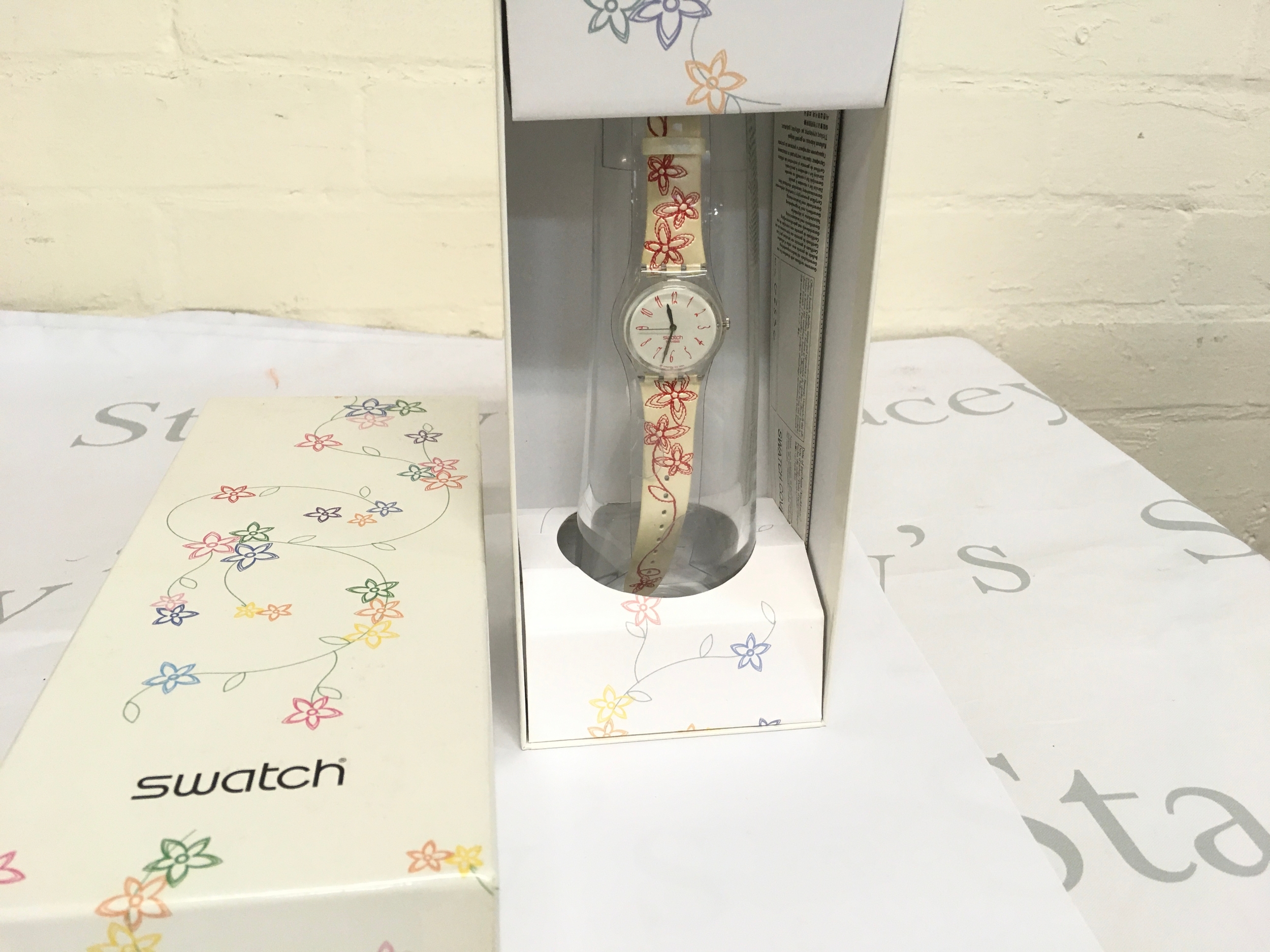 2004 Swatch "Motherly" (GZS36) watch, featuring a floral printed leather strap and a specialised glass container. It was released as a special edition for Mother's Day 2004. The watch has a case diameter of approximately 34 mm and runs on quartz movement.