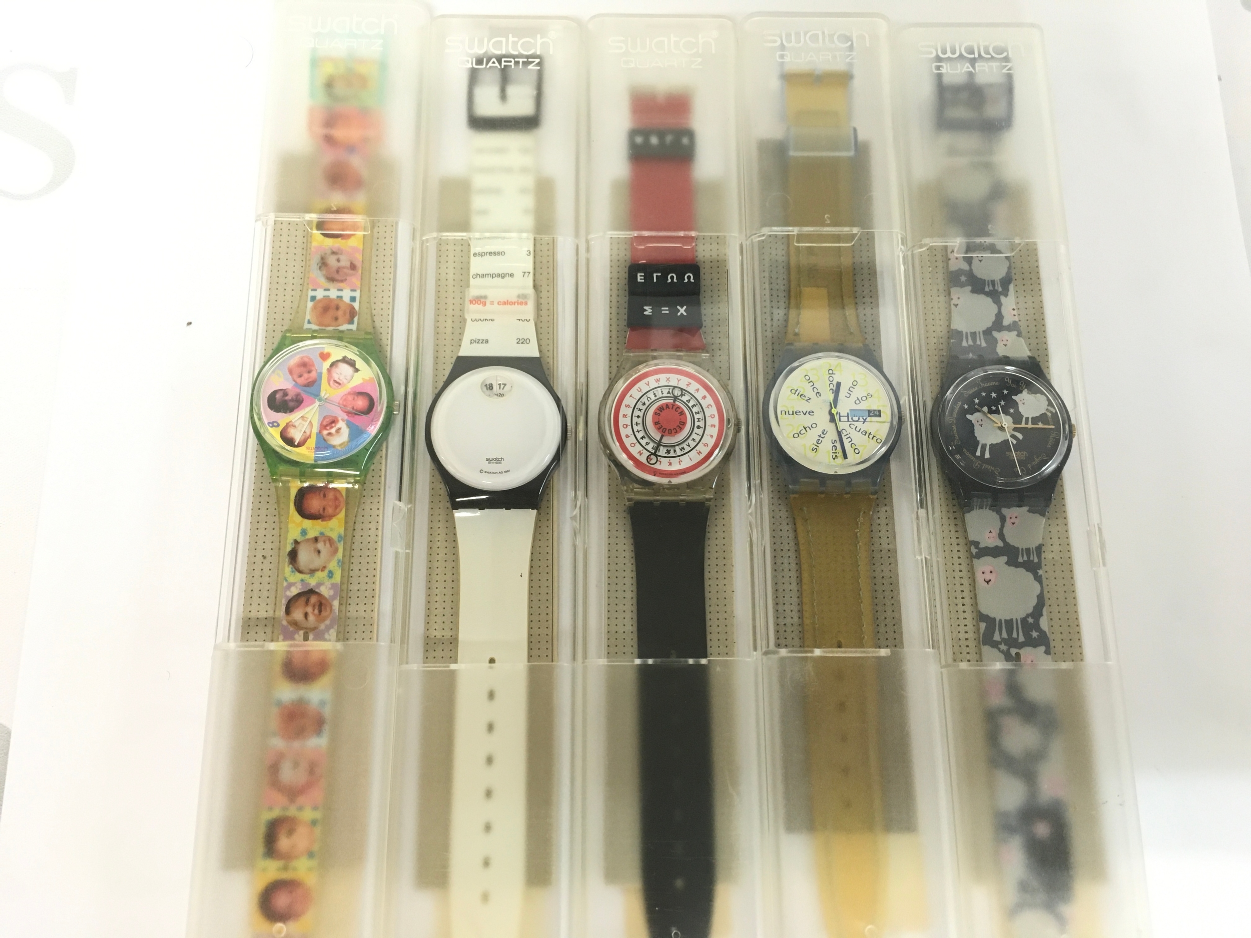collection features five vintage Swatch watches in their original clear plastic cases. The set includes notable designs like the Swatch Gent Calories.