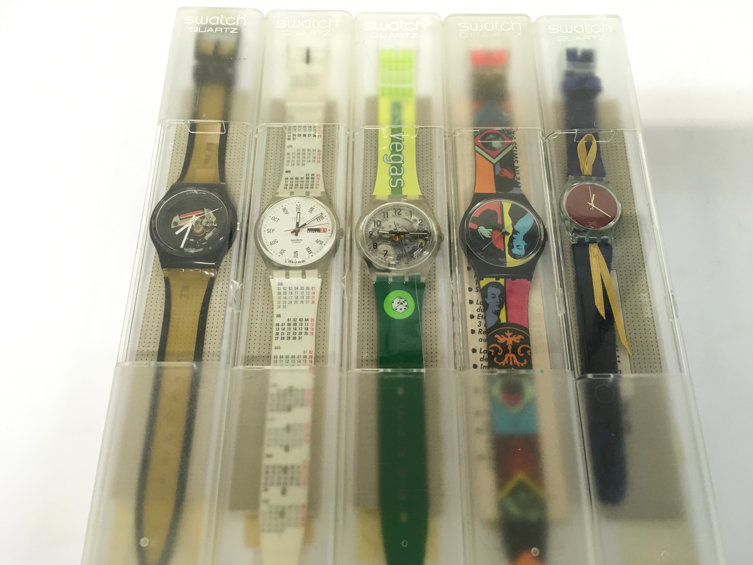 collection features various vintage Swatch Gent watches from the 1990s, complete with their original plastic display cases. Includes the "Calendarium" model, "Vegas" watch.