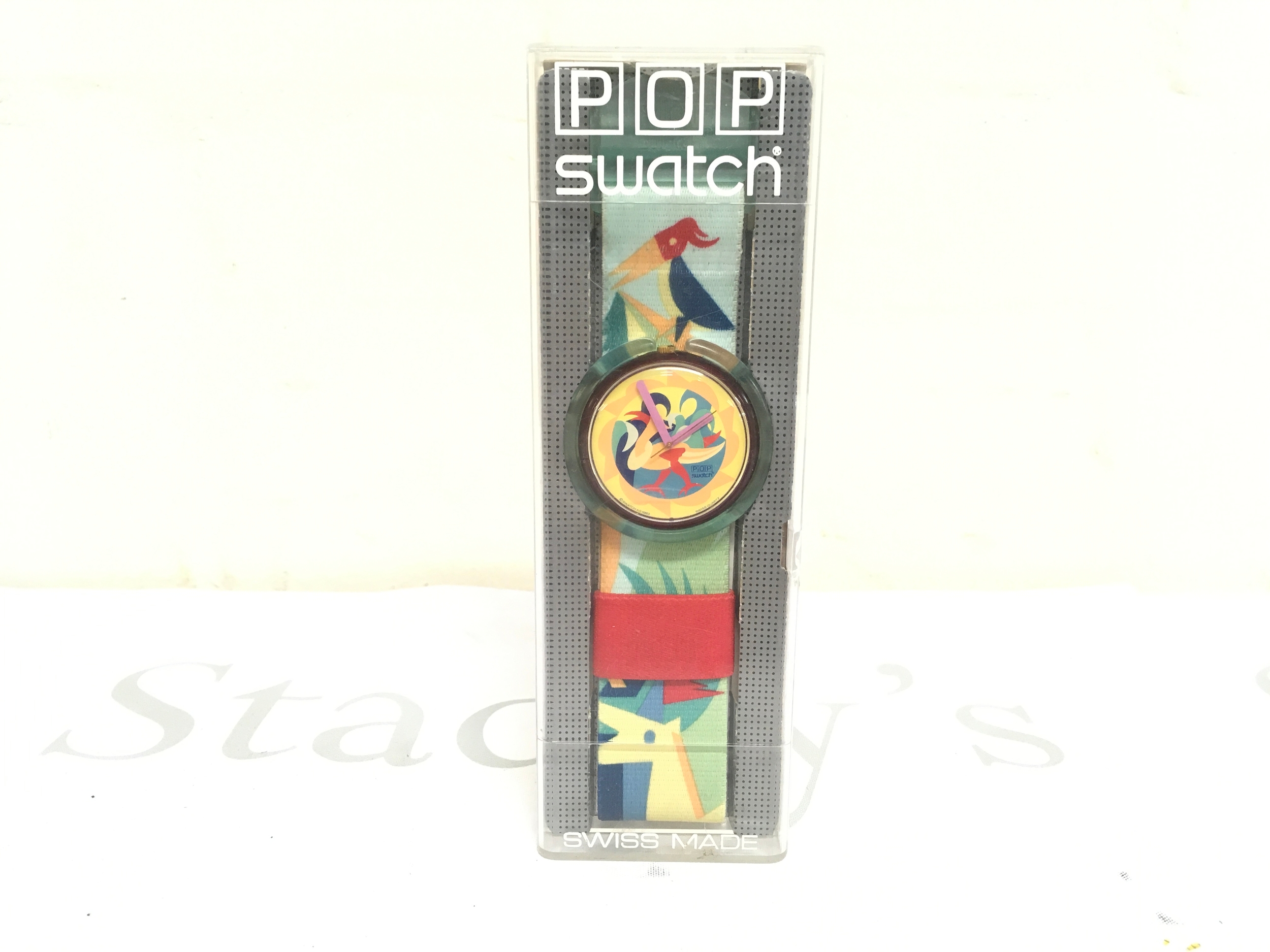 1993 Pop Swatch "The Woodleaker" (PWV102) watchwith a bird motif. It features a colorful strap and a yellow face, and is in its original packaging.